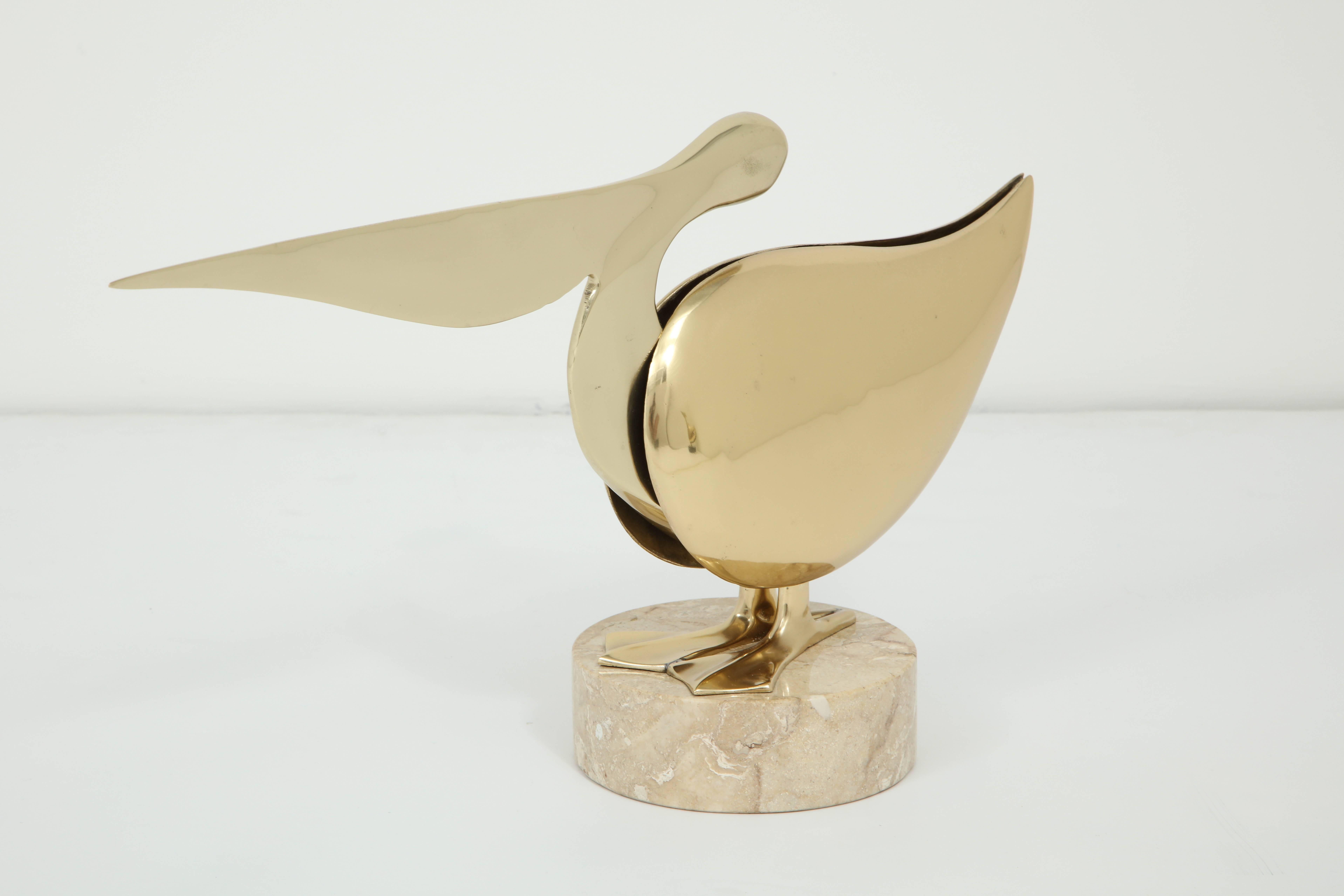 Decorative brass pelican sculpture displayed on a round marble base, Italy, circa 1950.