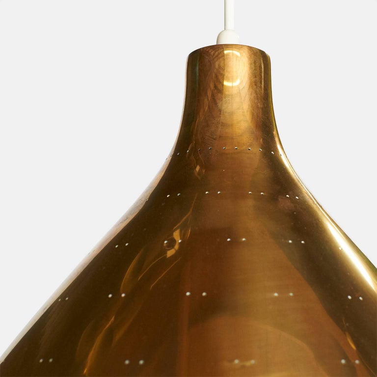 A large edition of the K2-46 chandelier by Paavo Tynell for Idman. The brass shade has twin dot perforations, scalloped edge detail, and a etched glass diffuser underneath. The overall length can be adjusted and specified,
Finland, circa 1950s.