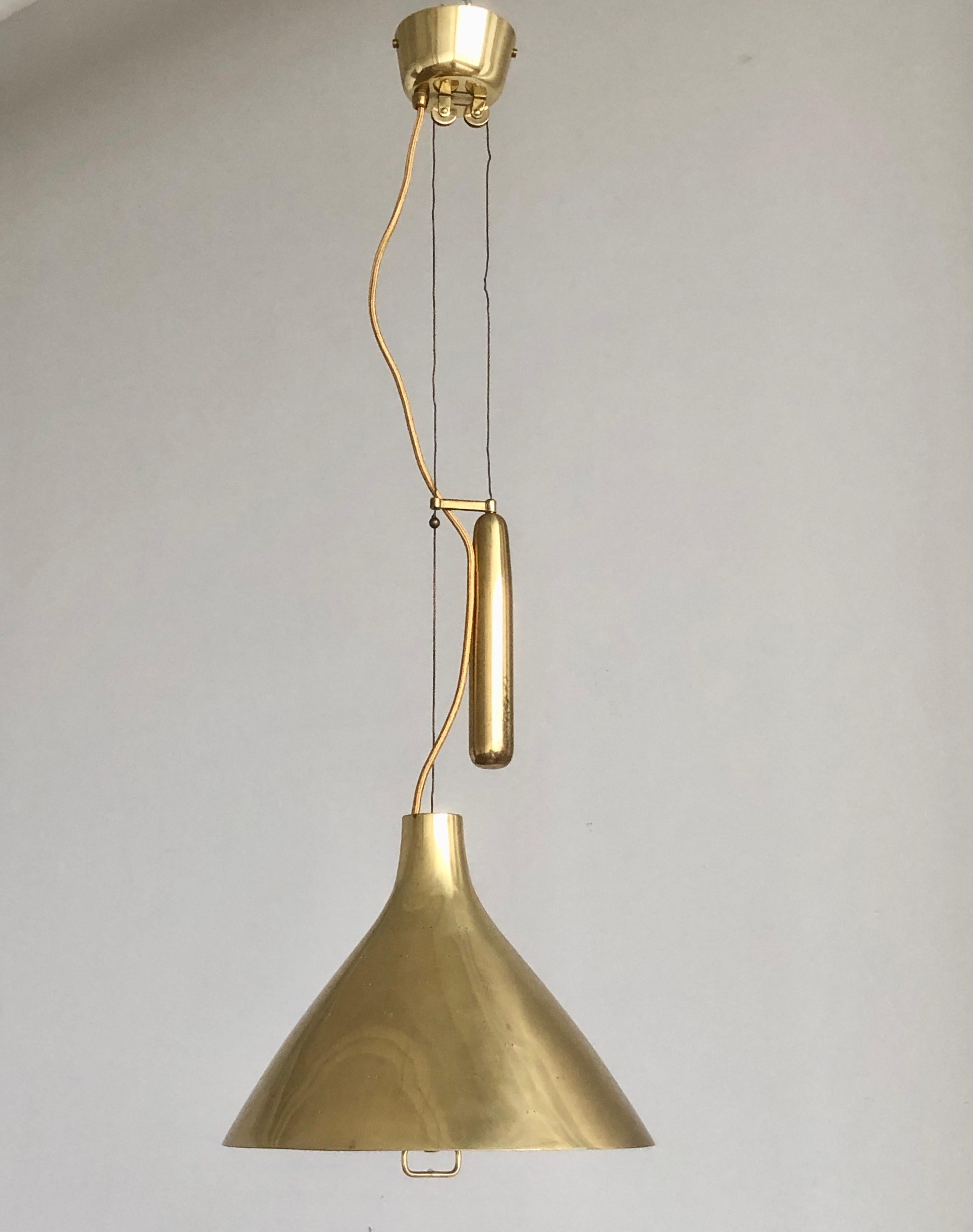 Large lighting pendant with counterweight designed by Paavo Tynell.
Perforated polished brass shade with frosted glass diffuser. Variation of model A1982, featured at Idman catalogue.  The height adjustable fro 40