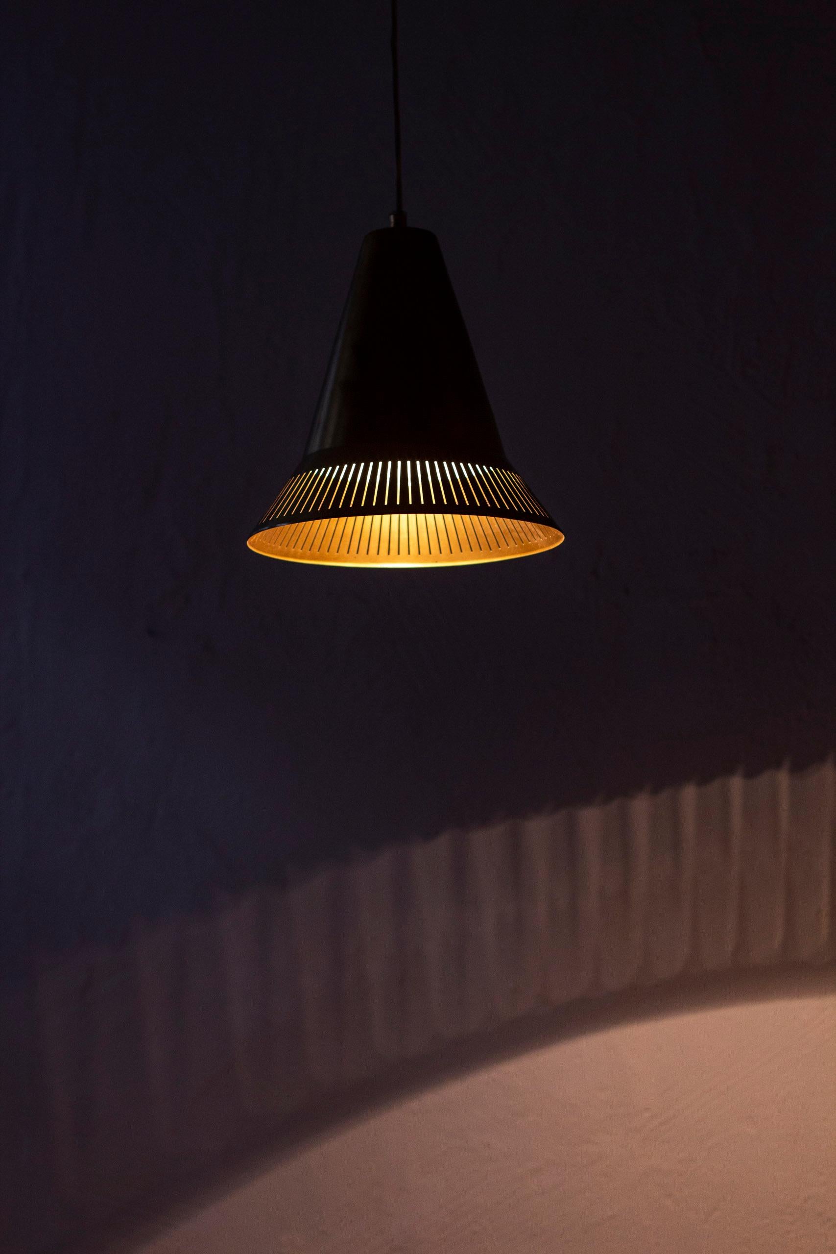 Pendant light model 100 designed by Hans Bergström. Produced by Ateljé Lyktan during the 1950s. Made from polished brass with white lacquered inside. Perforated edge and top creating a beautiful light when lit. Comes with original brass ceiling cup