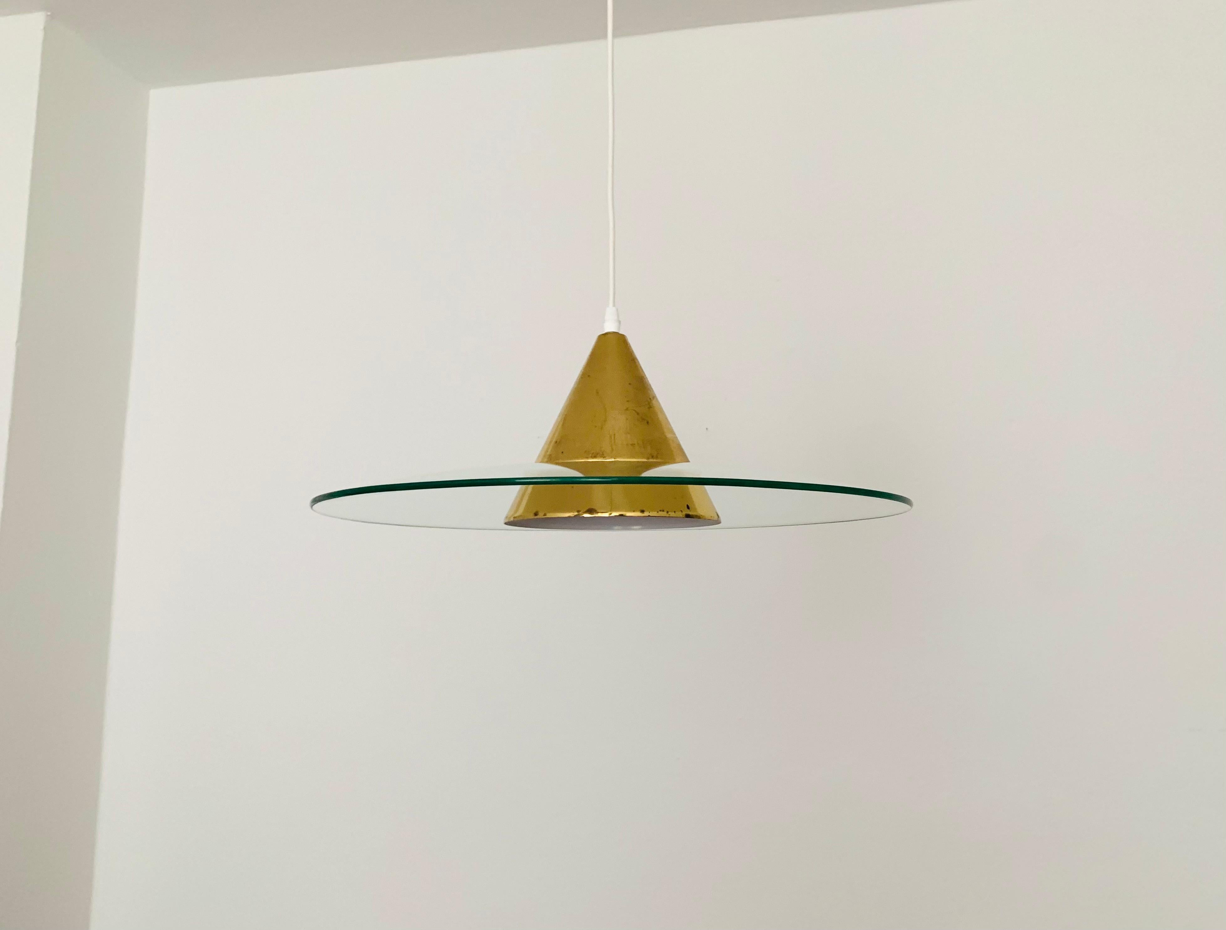 Impressionante lampada a sospensione degli anni '60.
Il design e l'aspetto della lampada sono particolarmente belli.
Il vetro viene illuminato attraverso le fessure luminose del cono di alluminio.
Si crea un effetto di luce molto