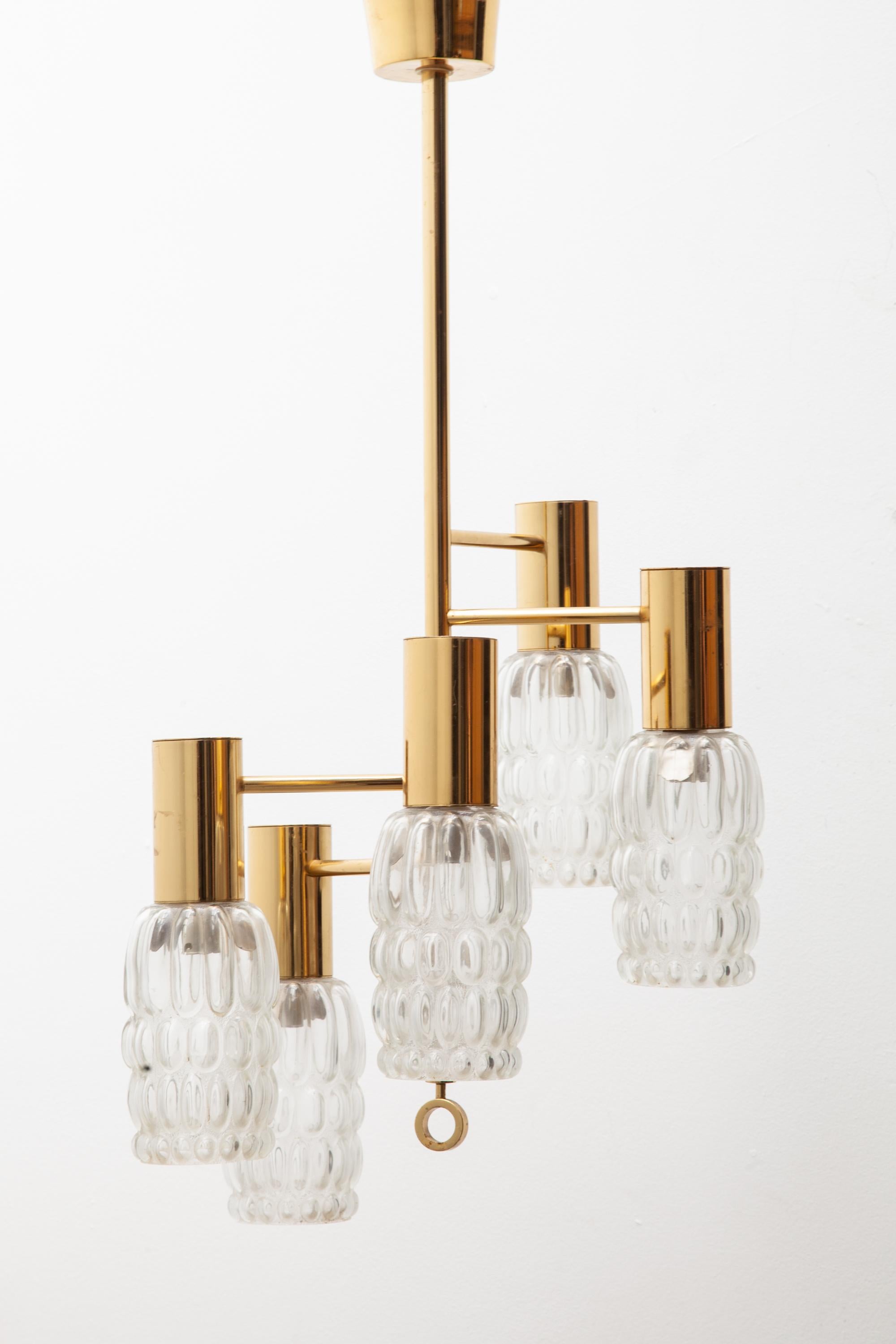 A beautiful polished brass pendant light fixture by Helena Tynell for Glashütte Limburg, Germany.
Five clear bubble glass lamp shades hang on polished brass arms.
Very good original condition.