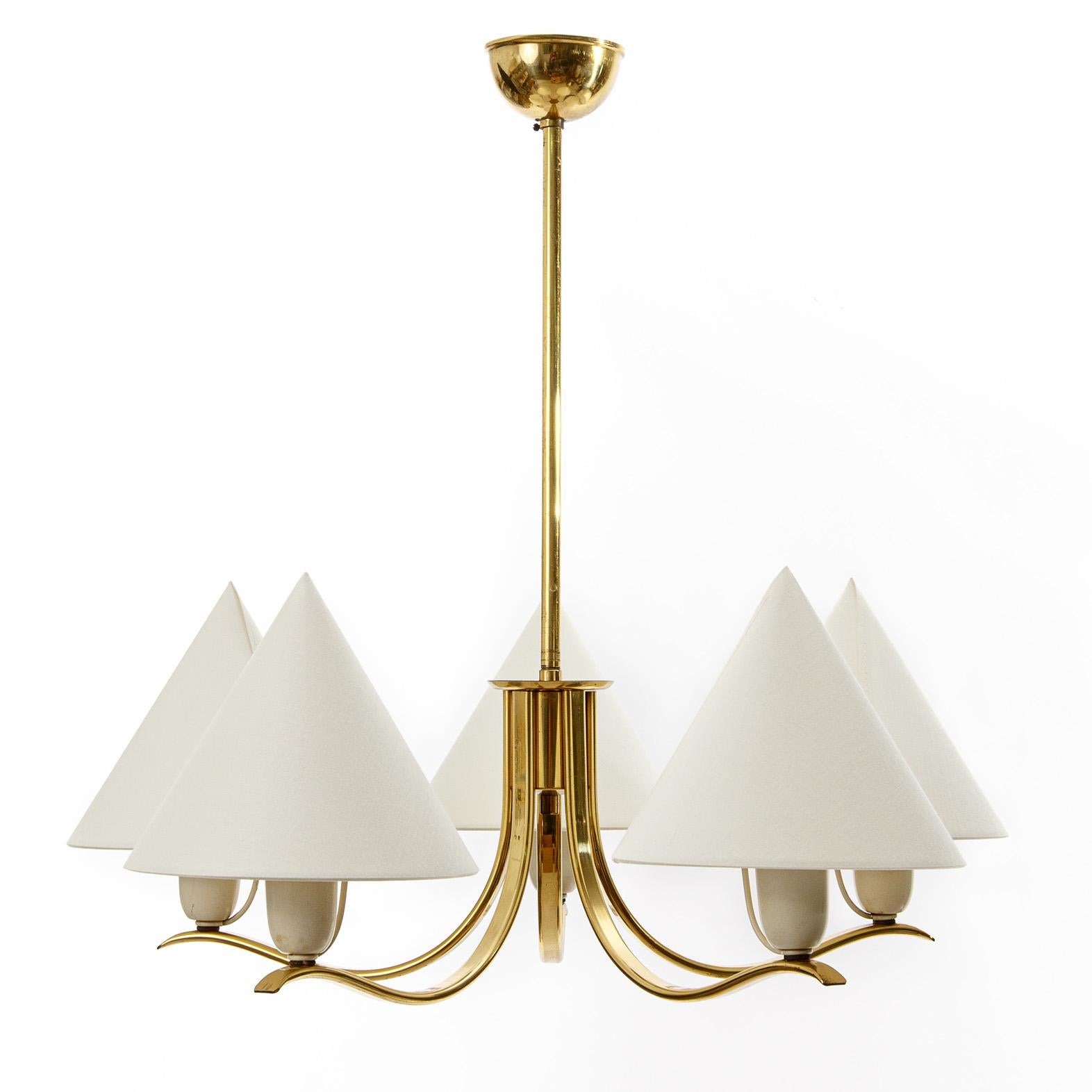 A brass chandelier with five organic shaped arms and cone-shaped lampshades by Rupert Nikoll, Vienna, Austria, manufactured in midcentury, in 1950s.
The brass parts have a warm aged hue. There is little wear on the white bulb socket covers.
The lamp