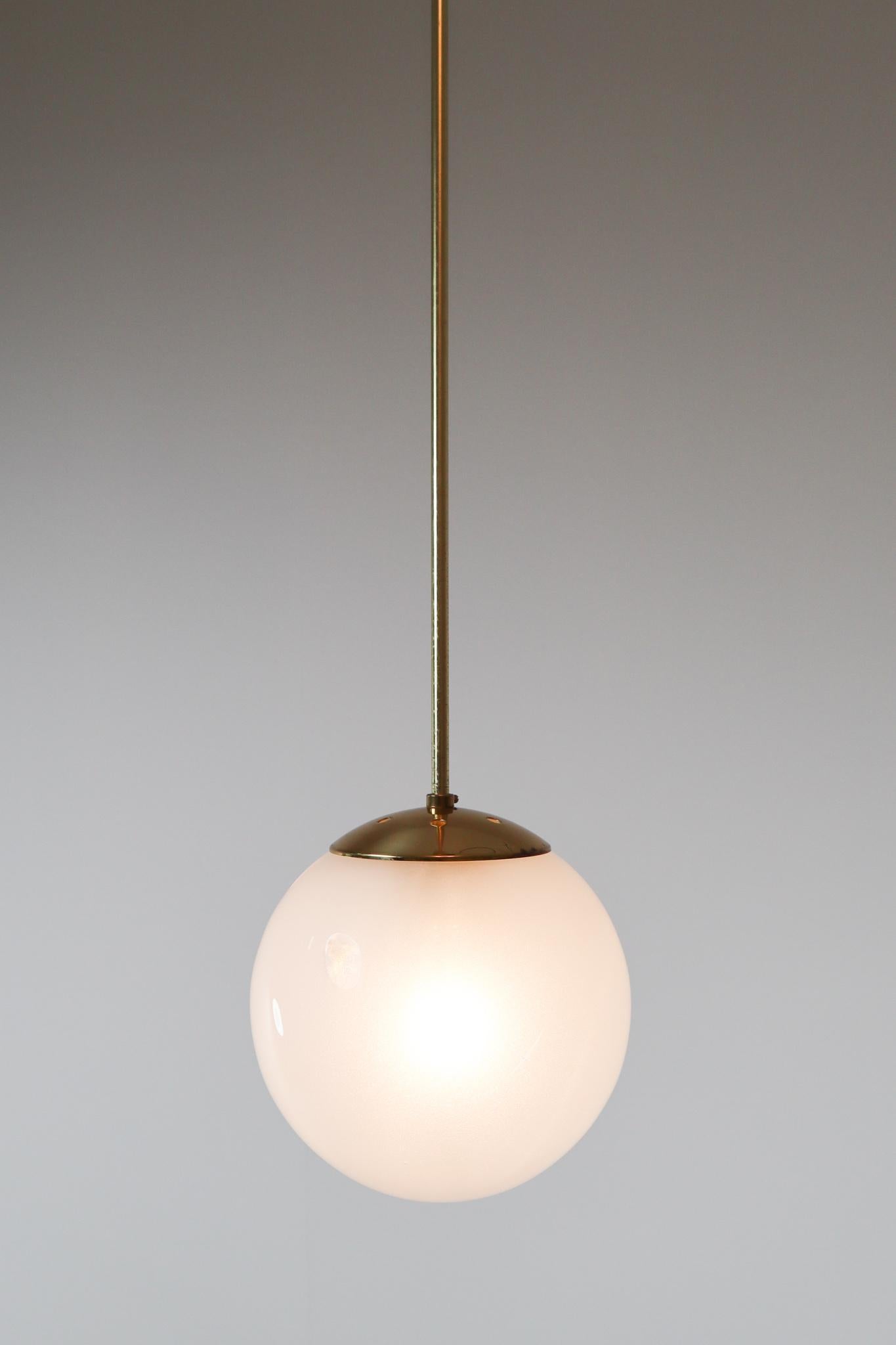 Elegant brass pendant by designer and manufacturer Preciosa Kamenický Šenov and produced in Czech Republic the early 1970s. Beautiful work with a pearl hand blown globe hanging by a brass rod. This pendant will create an absolute stunning light