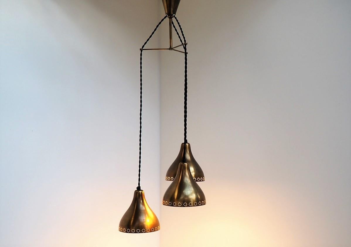 Set of 3 lovely patinated brass pendants hanging in brass suspension including brass canopy. The pendants has a decorative hole pattern which appears even more when the light is on.

The pendants hang here in different heights and would be perfect