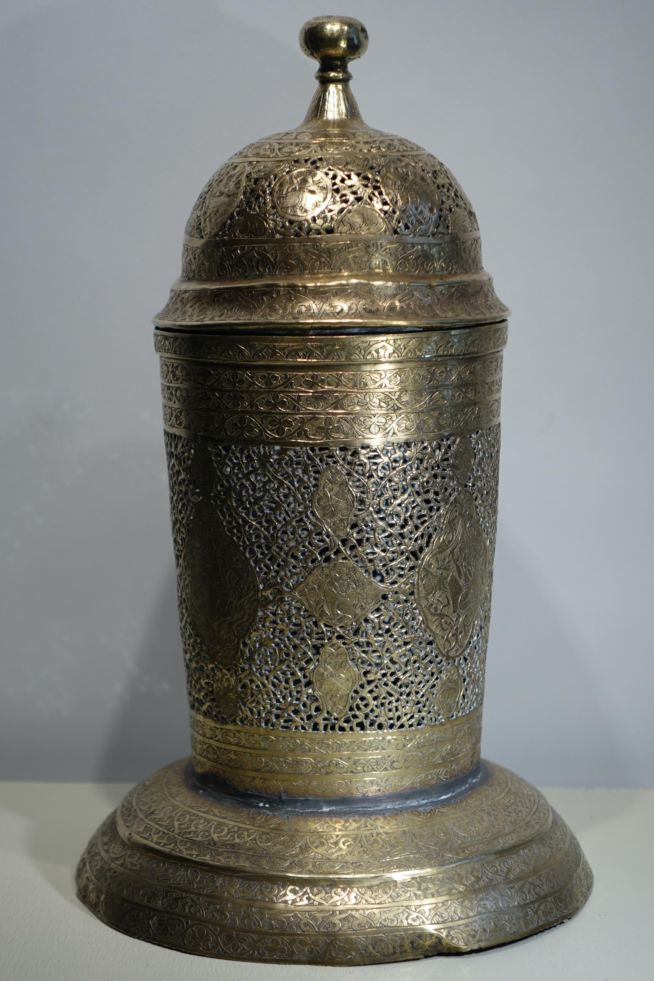 Brass incense burner with openwork decoration of interlacing, scrolls and foliage.
Four registers on the body depict zoomorphic and anthropomorphic patterns.
The base has been re-assembled to the body, otherwise in good condition.
Persia, 19th