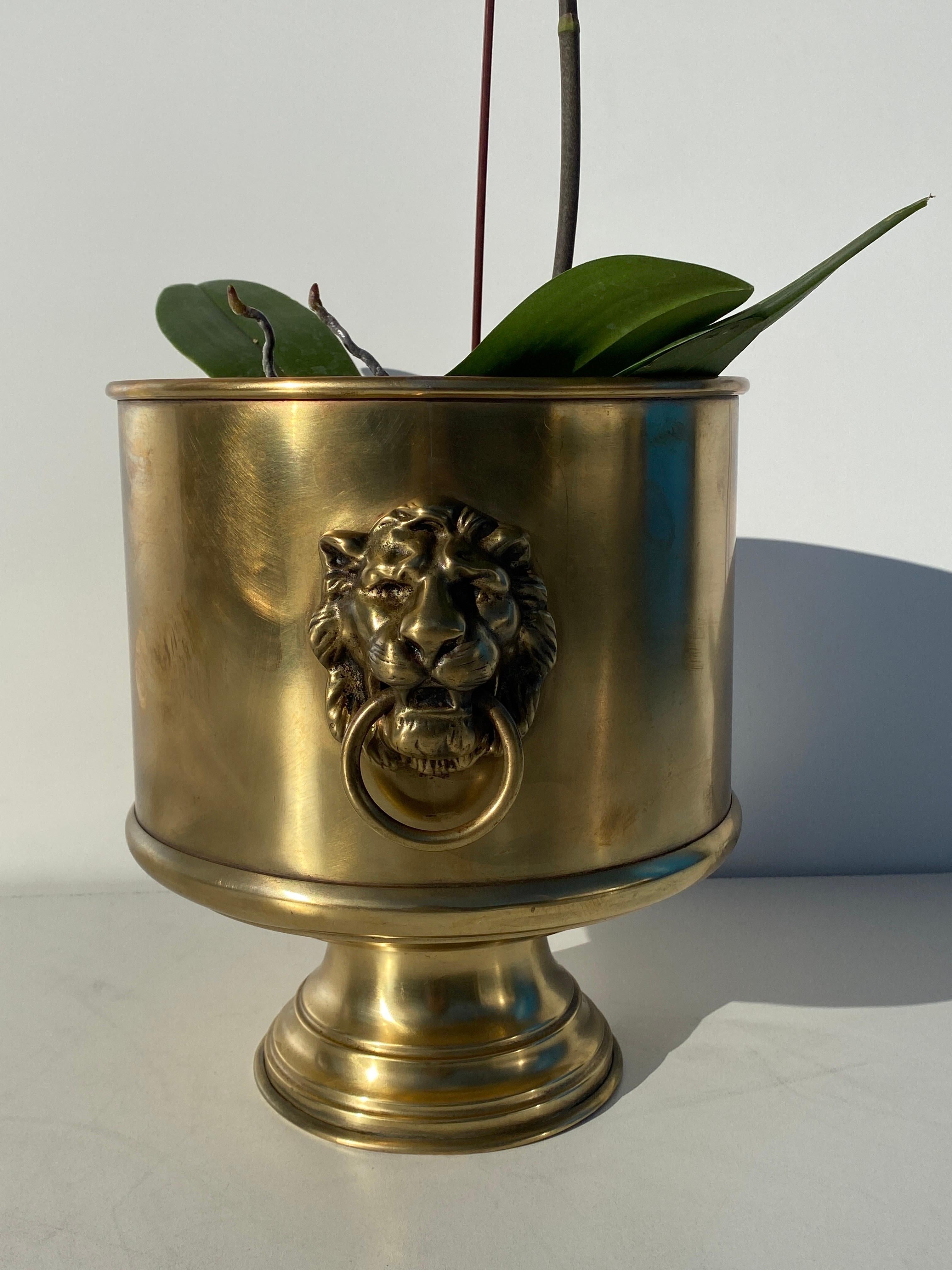 Round brass planter with lion motif.