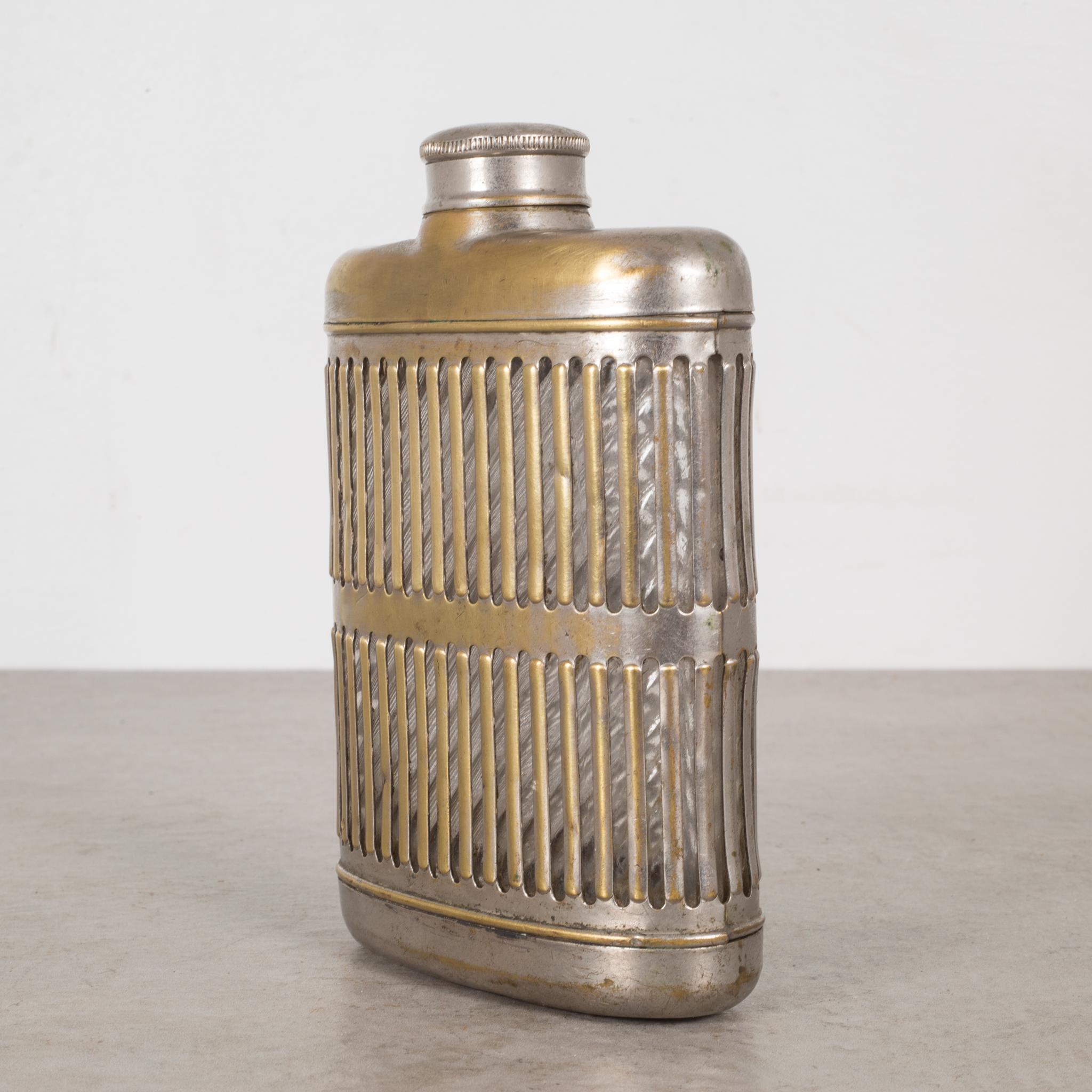 ABOUT

A brass plated caged metal flask with screw top lid and glass interior.

 CREATOR Unknown.
 DATE OF MANUFACTURE c.1920.
 MATERIALS AND TECHNIQUES Brass Plated Metal, Glass.
 CONDITION Good. Wear consistent with age and use. Glass is