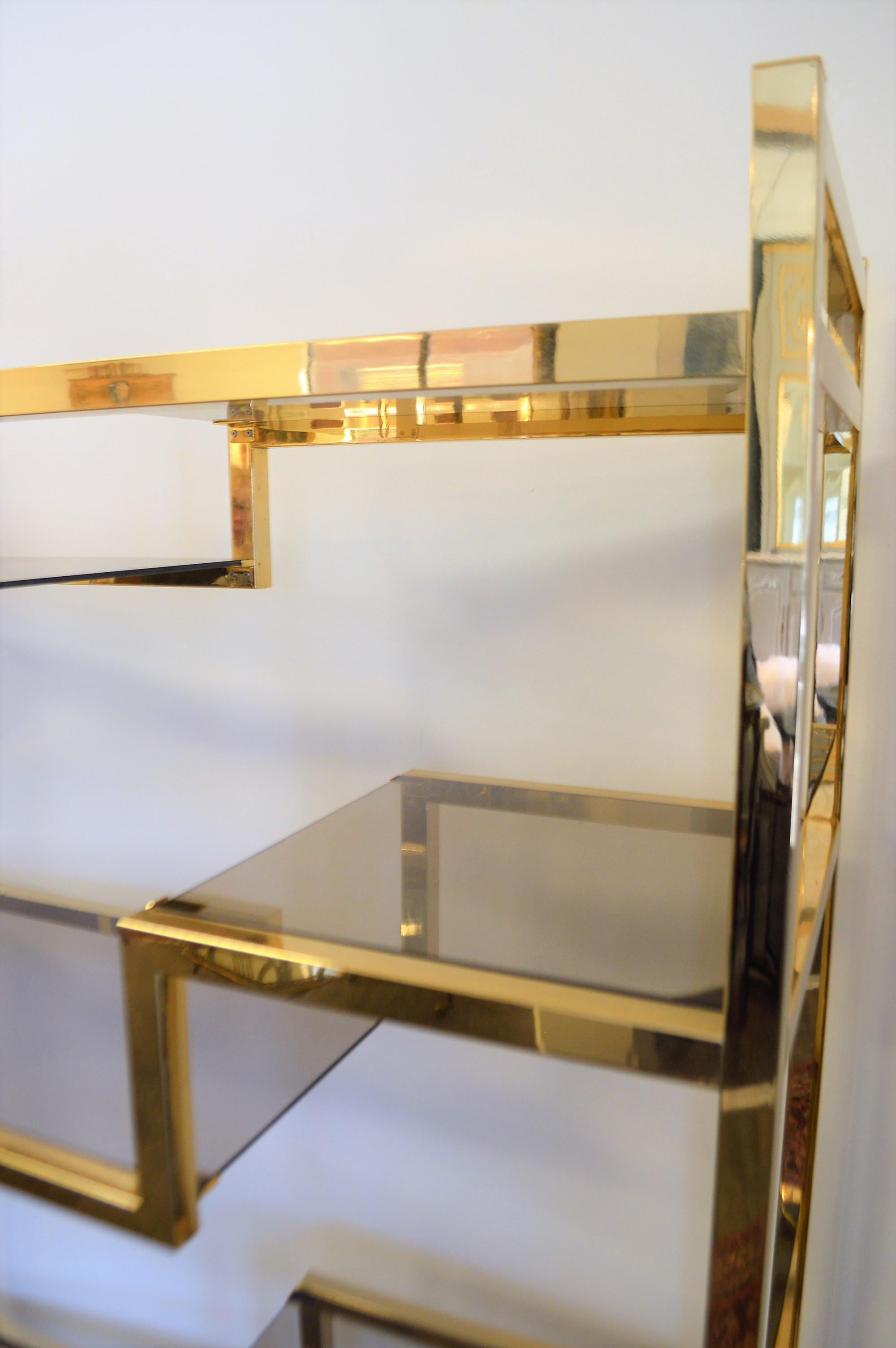 Attractive and modern style brass plated étagère. The brass has a rich tone of gold. The étagère is sturdy. There are 6 smoke glass in half shelves, the lower one is a full shelf.
The shelves placement are not movable.
It is difficult to