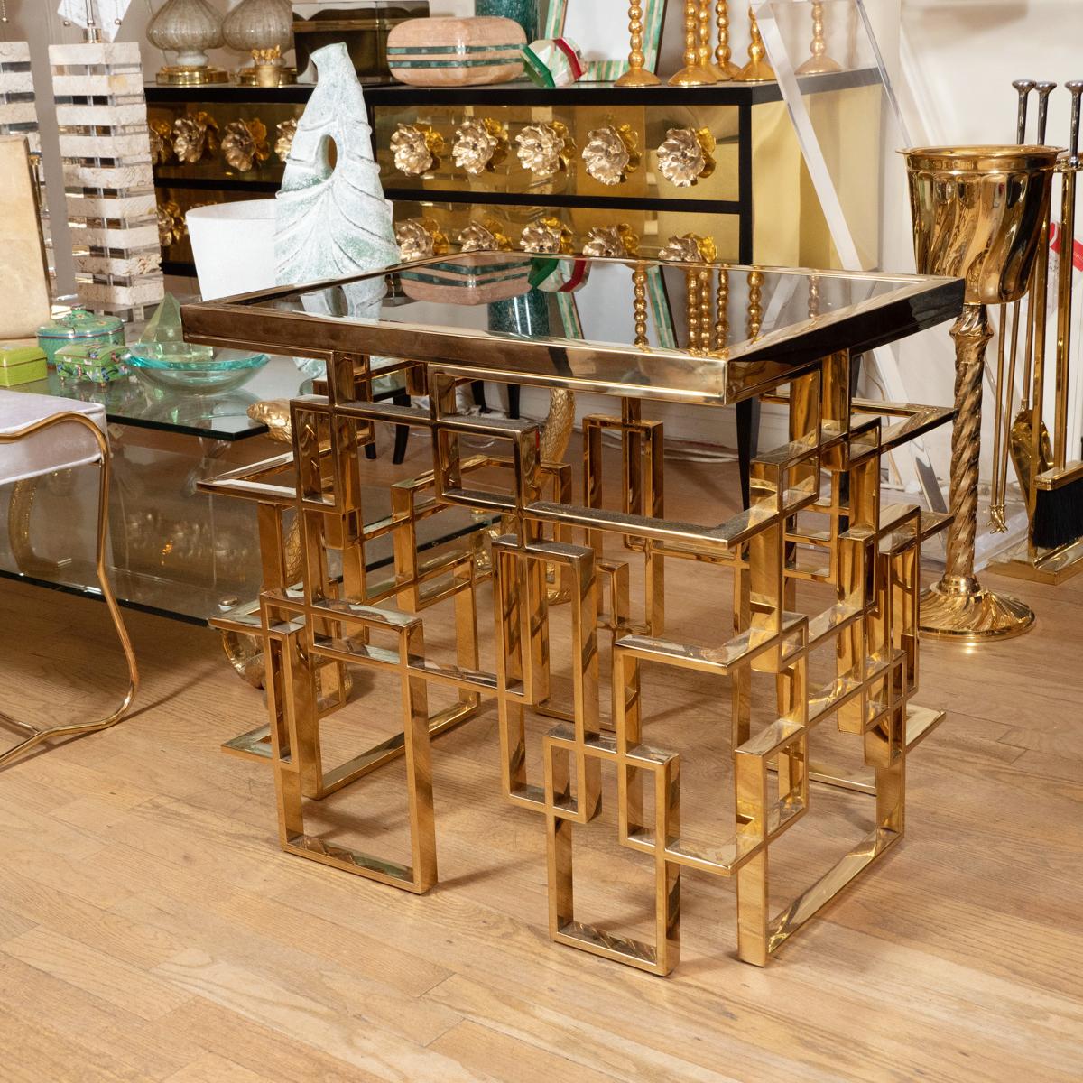 Brass plated metal side table with geometric design base and smoked glass top.