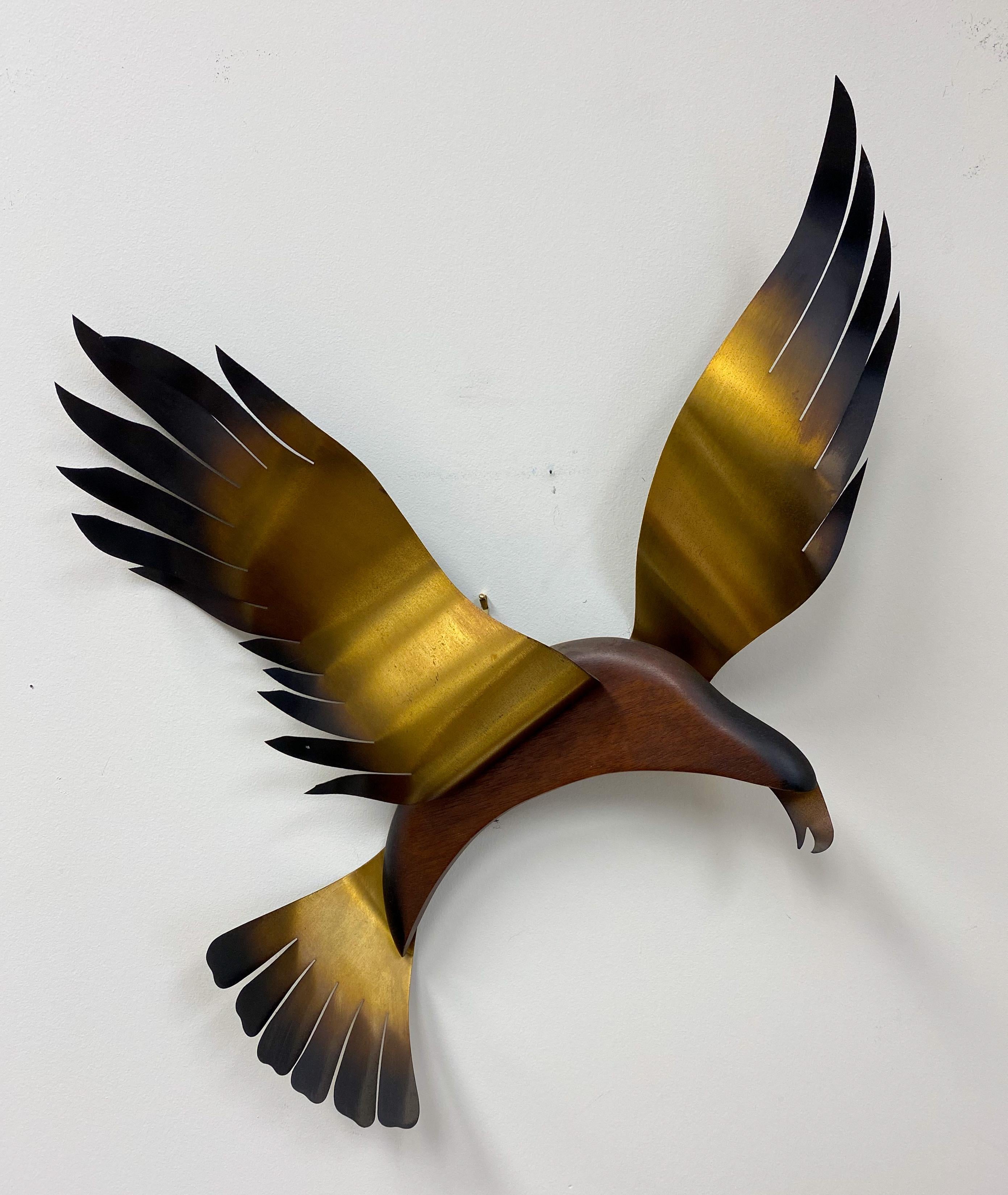 A beautiful pair of brass plated in flight seagulls wall hanging sculpture attributed to Curtis Jere. The birds wings and tails are in brass and the body in wood. The mid-century modern seagulls sculptures are finely hand-carved and highly