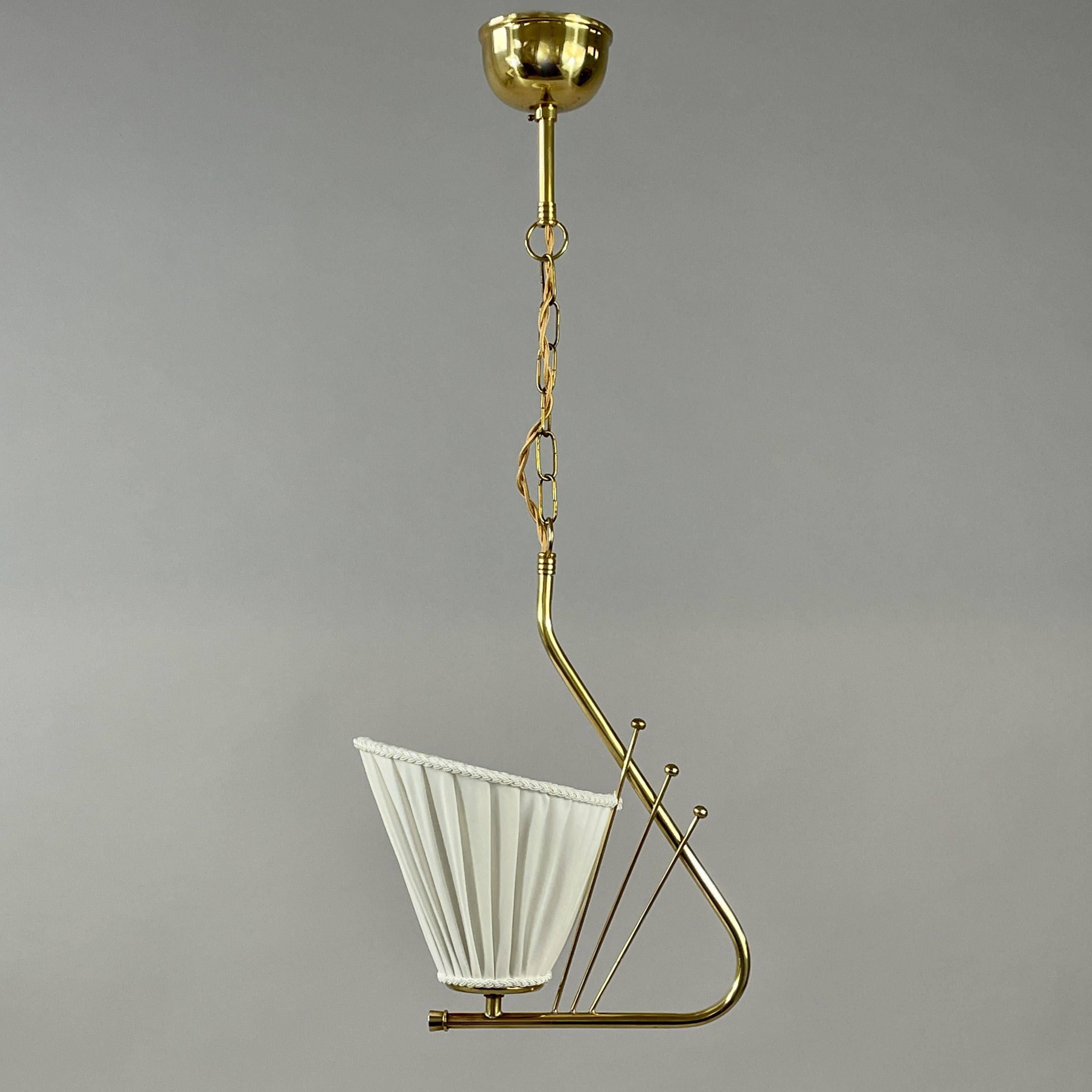 Cette élégante suspension a été conçue et fabriquée en Suède dans les années 1940.

Le luminaire présente une élégante structure en laiton à la forme sculpturale et asymétrique qui s'incurve doucement vers le bas pour soutenir un abat-jour conique