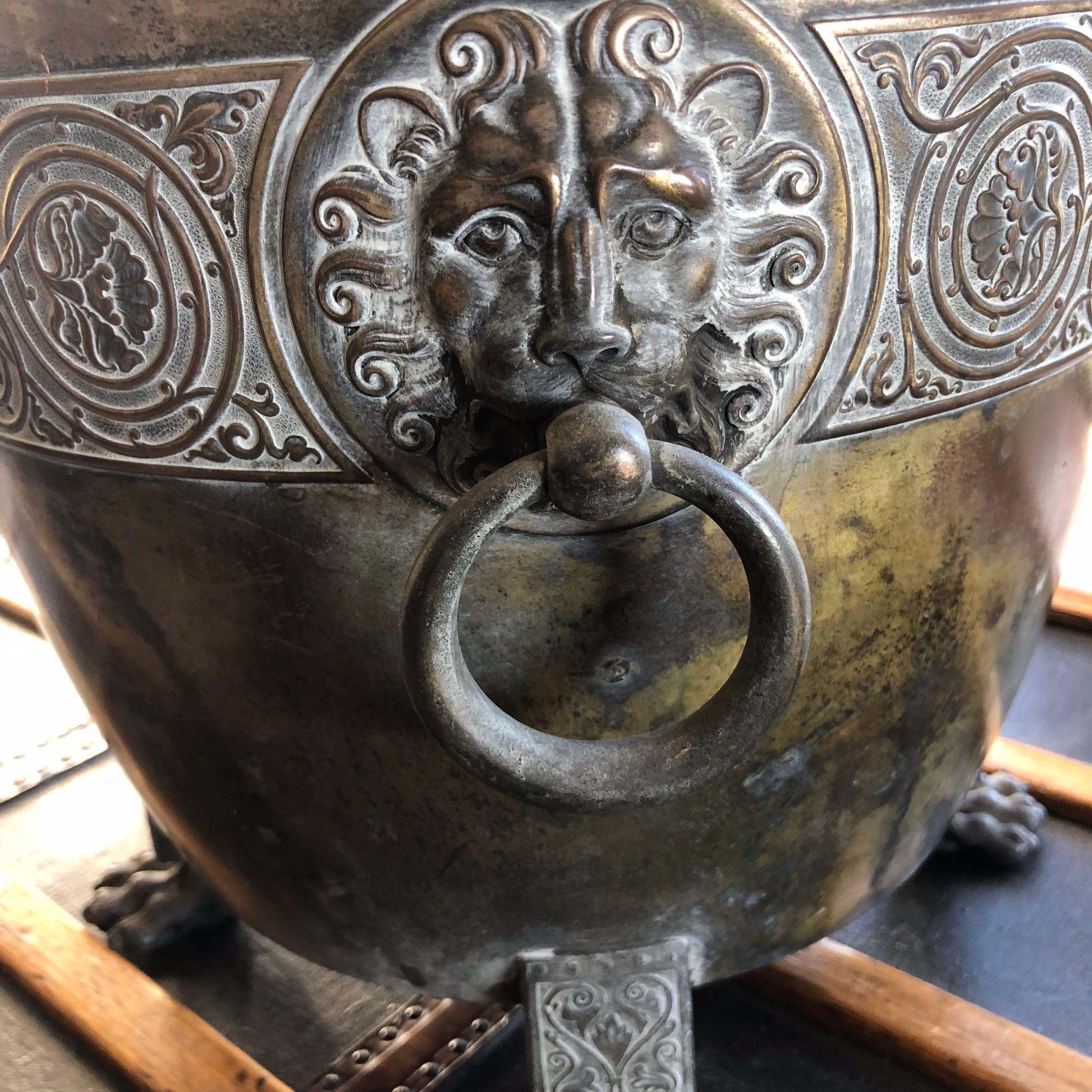 A brass pot/planter with decorative lion carvings on paw feet.