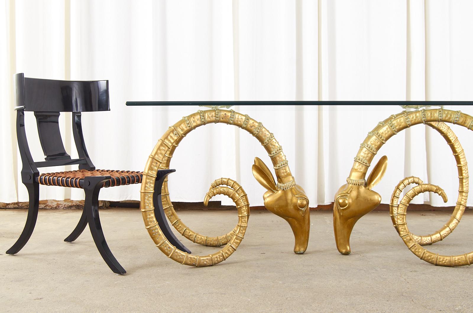 Sculptural French brass dining table attributed to Alain Chervet featuring a pair of large ram's head ibex forms. Remarkable size gives a dramatic focal point with beautifully detailed horns. Topped with a very thick pane of rectangular glass having