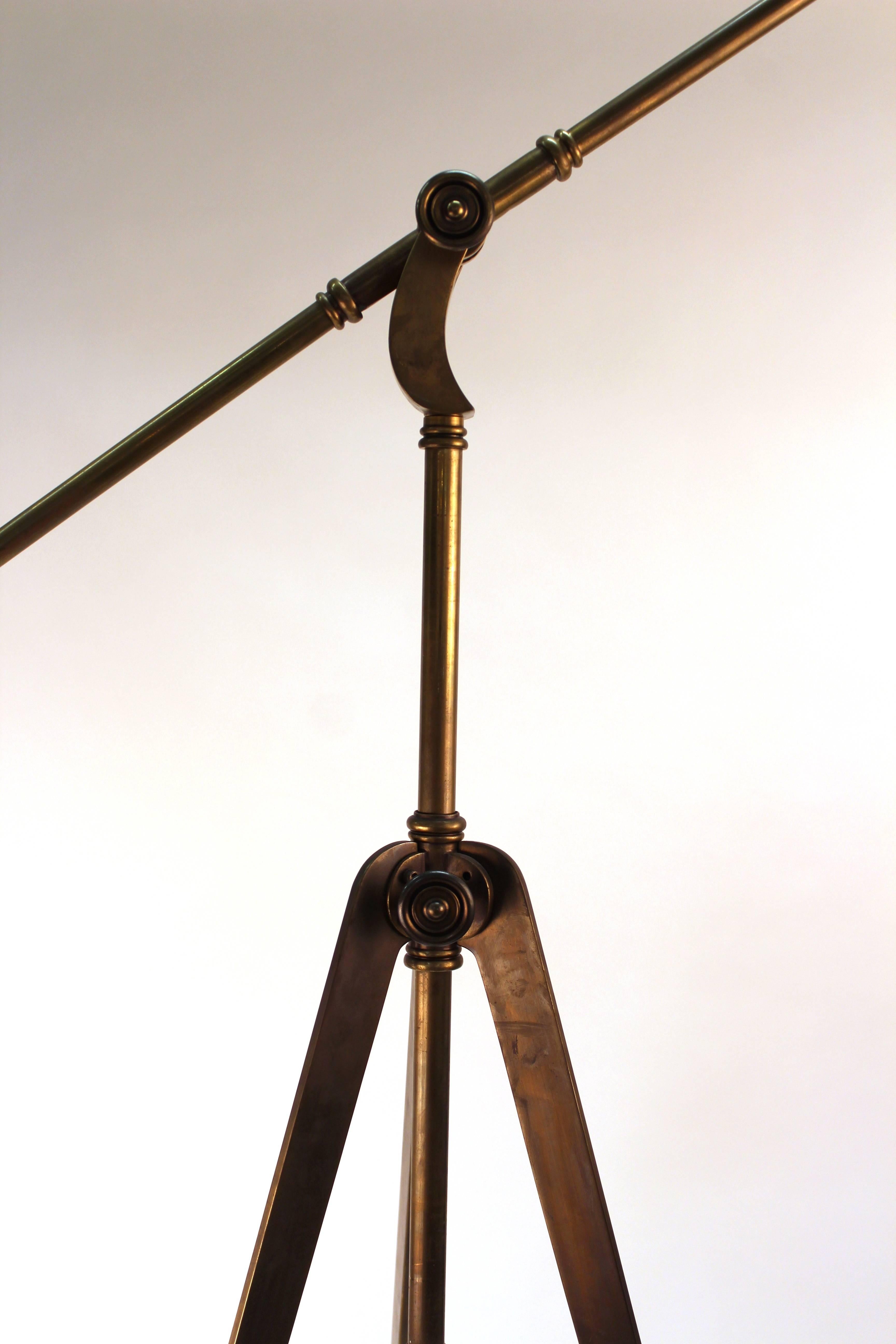 Industrial style reading lamp. Adjustable neck stands on a tripod base. Completely crafted in patinated brass. Wear appropriate to age and use. The lamp is in good condition.