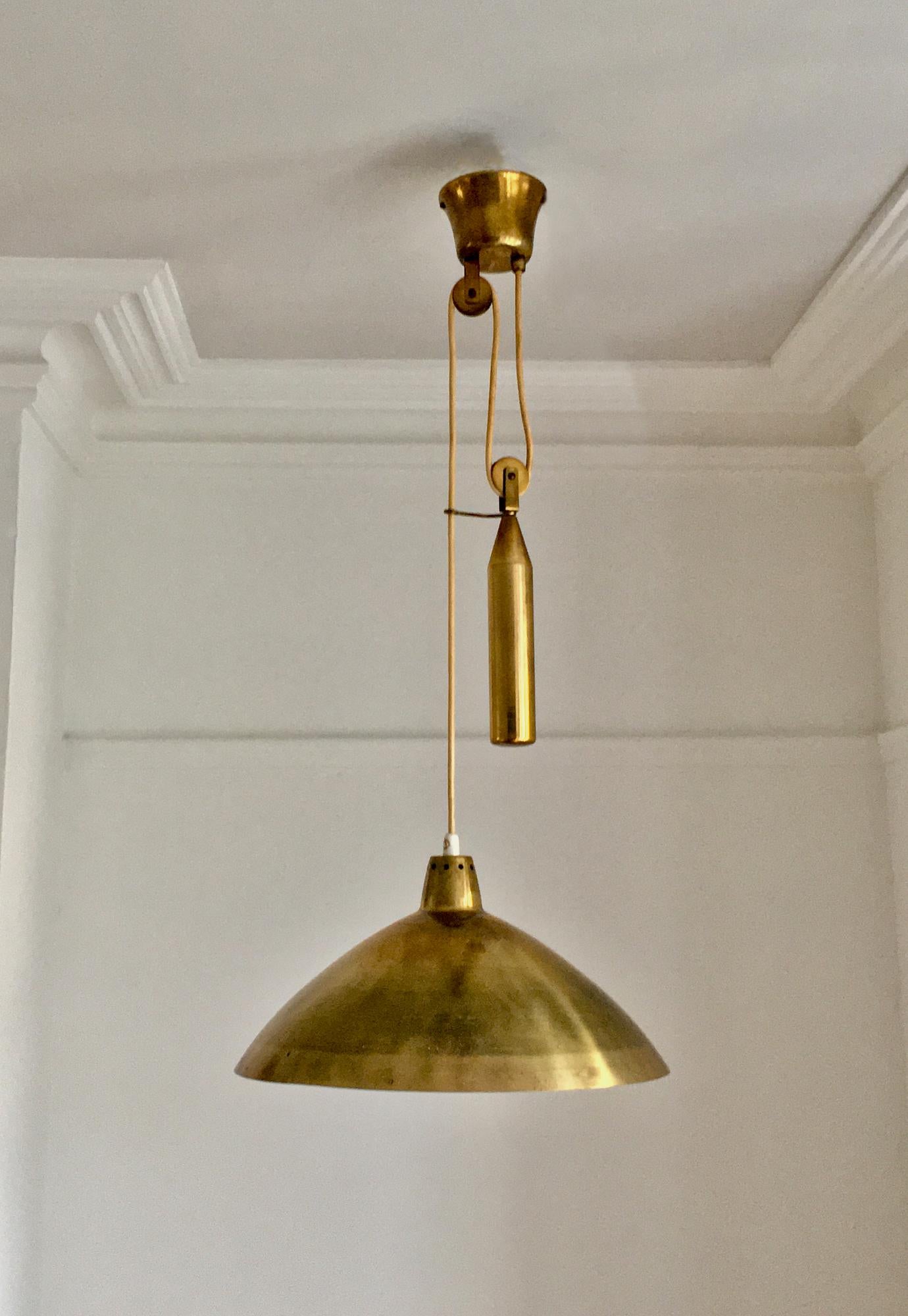 Mid-century brass rise and fall chandelier, produced by Itsu of Finland. 

A simple and elegant chandelier featuring a large perforated brass shade - off-white on the inside - with a rise and fall counter-balance weight, also in brass. High quality