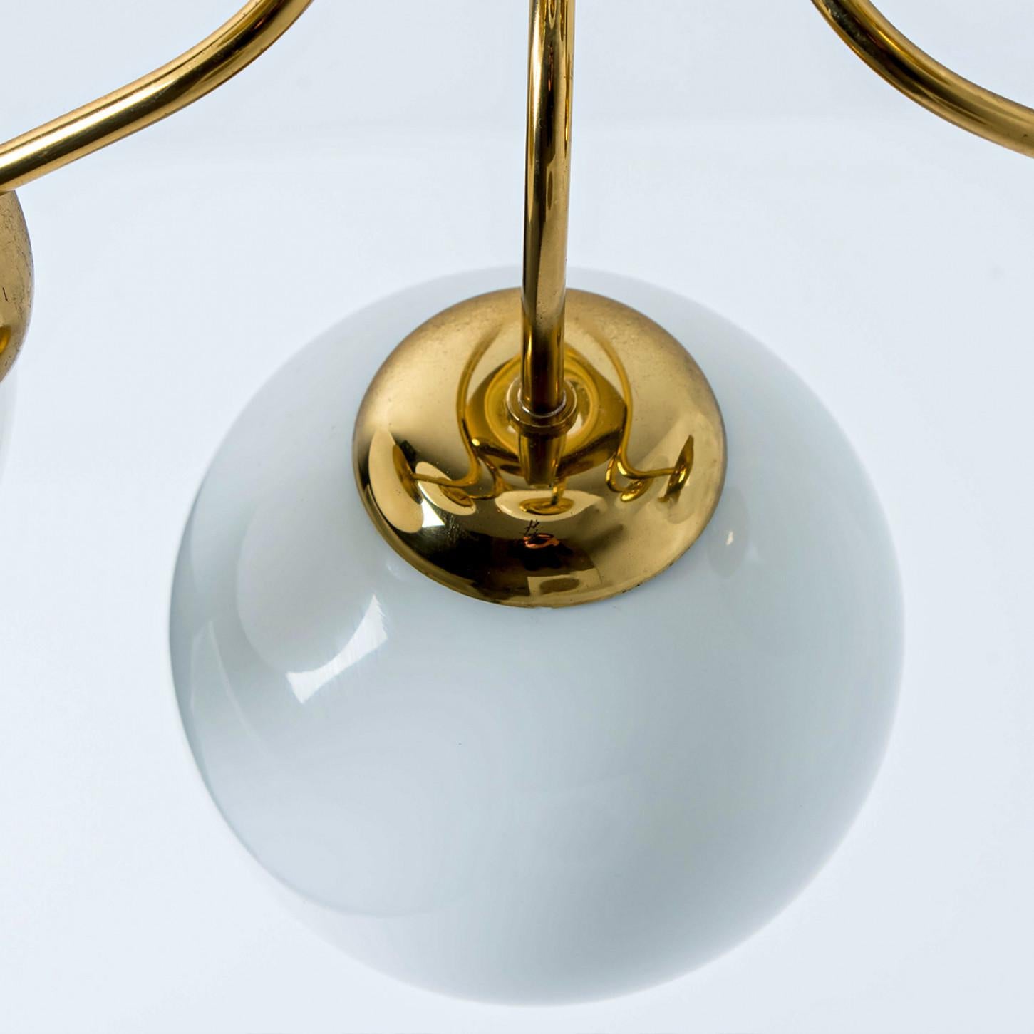 A wonderful round brass chandelier, circa 1970, made by Glashütte Limburg, Germany.
With hand-blown white glass on a brass base and a curve-like structure in brass. Illuminates beautifully.

Dimensions:
Diameter: 21.65