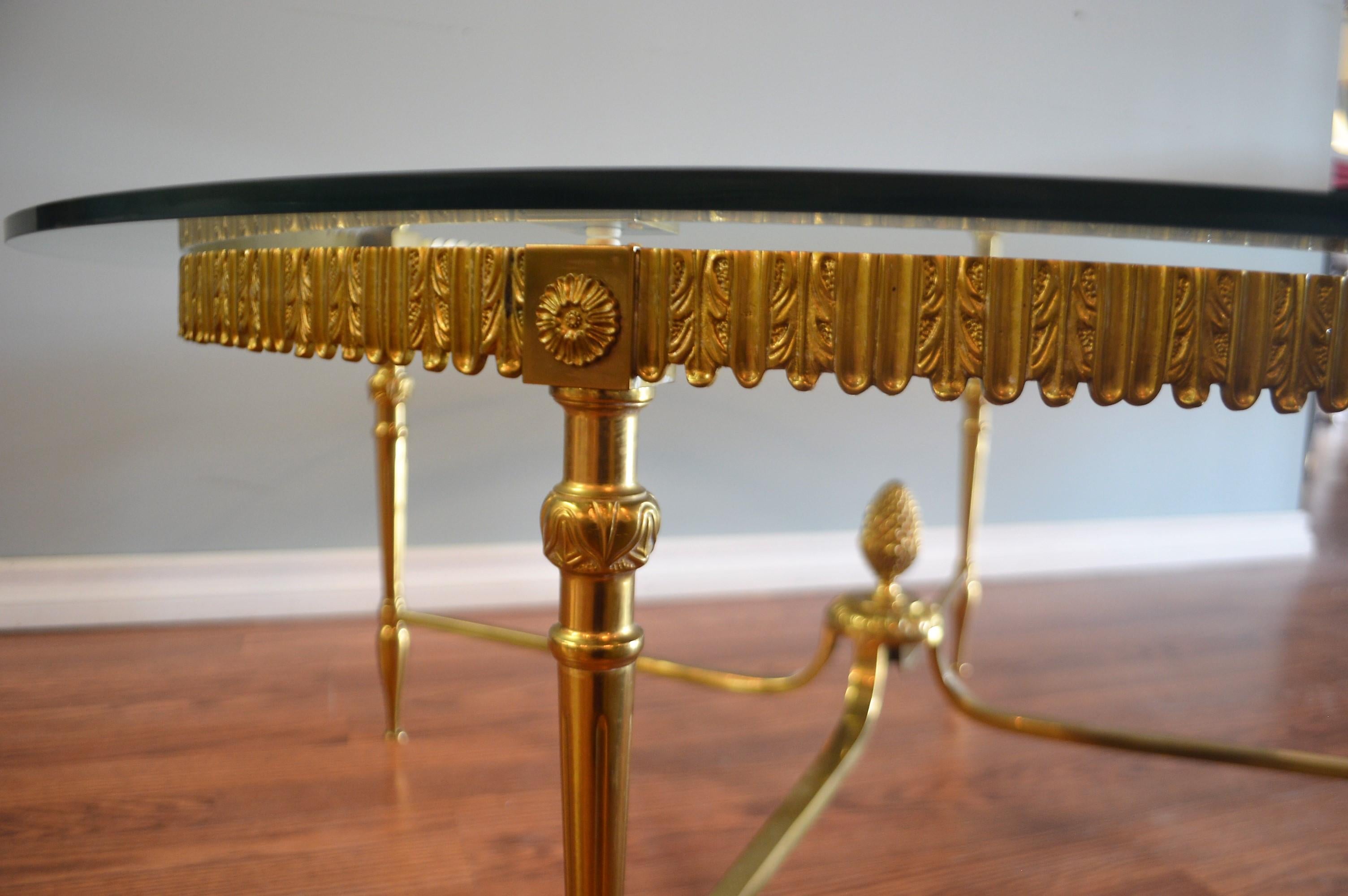 Elegant and unusual round frame coffee table having an ornate apron and
attractive cross lower frame with brass pineapple center and glass top.
 