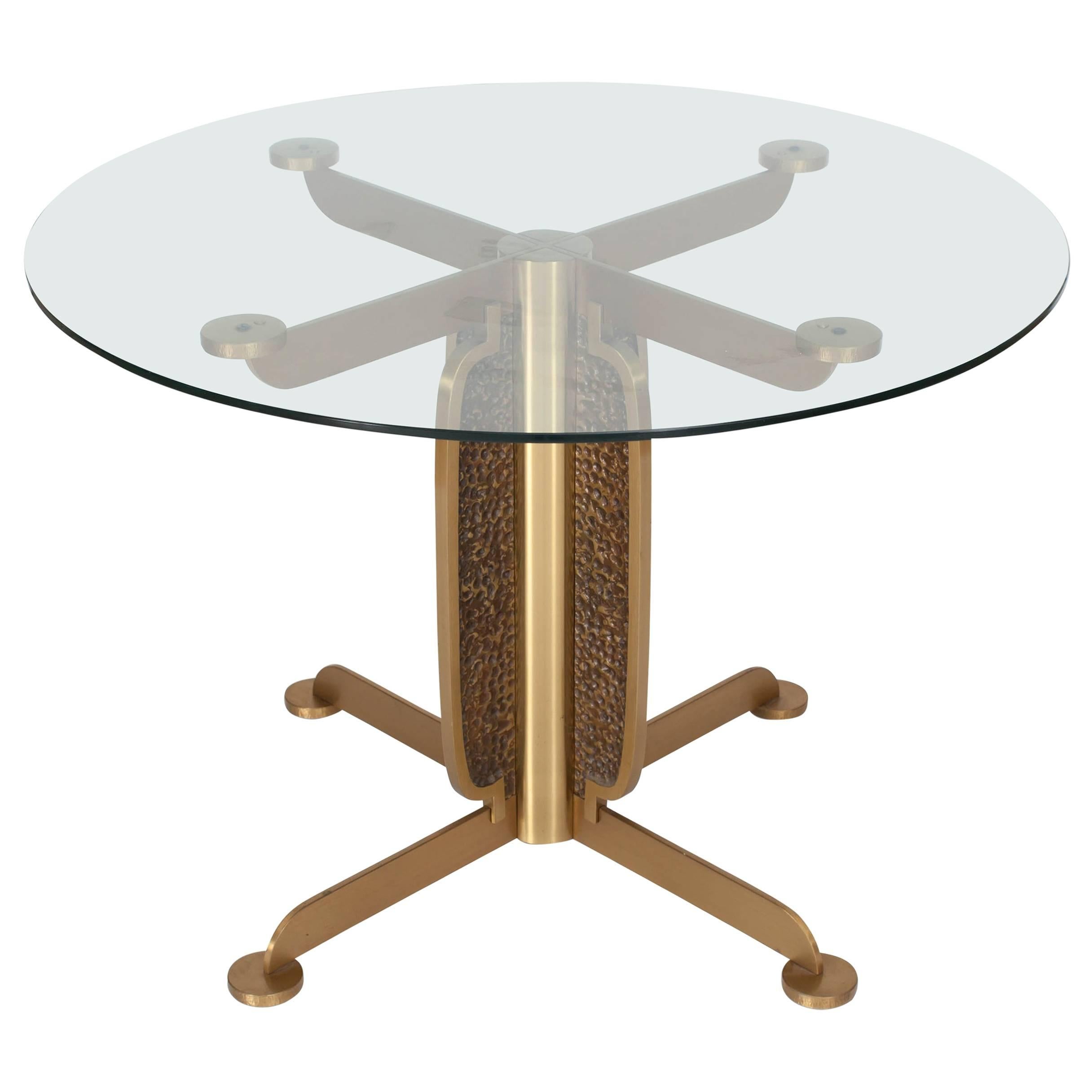 Postmodern sculptural brass cast dining table with glass top, Luciano Frigerio, Italy, 1970s.

The cross shaped brass frame consist out of two different structures and give the item an Brutalist appearance.

Would fit well in an eclectic