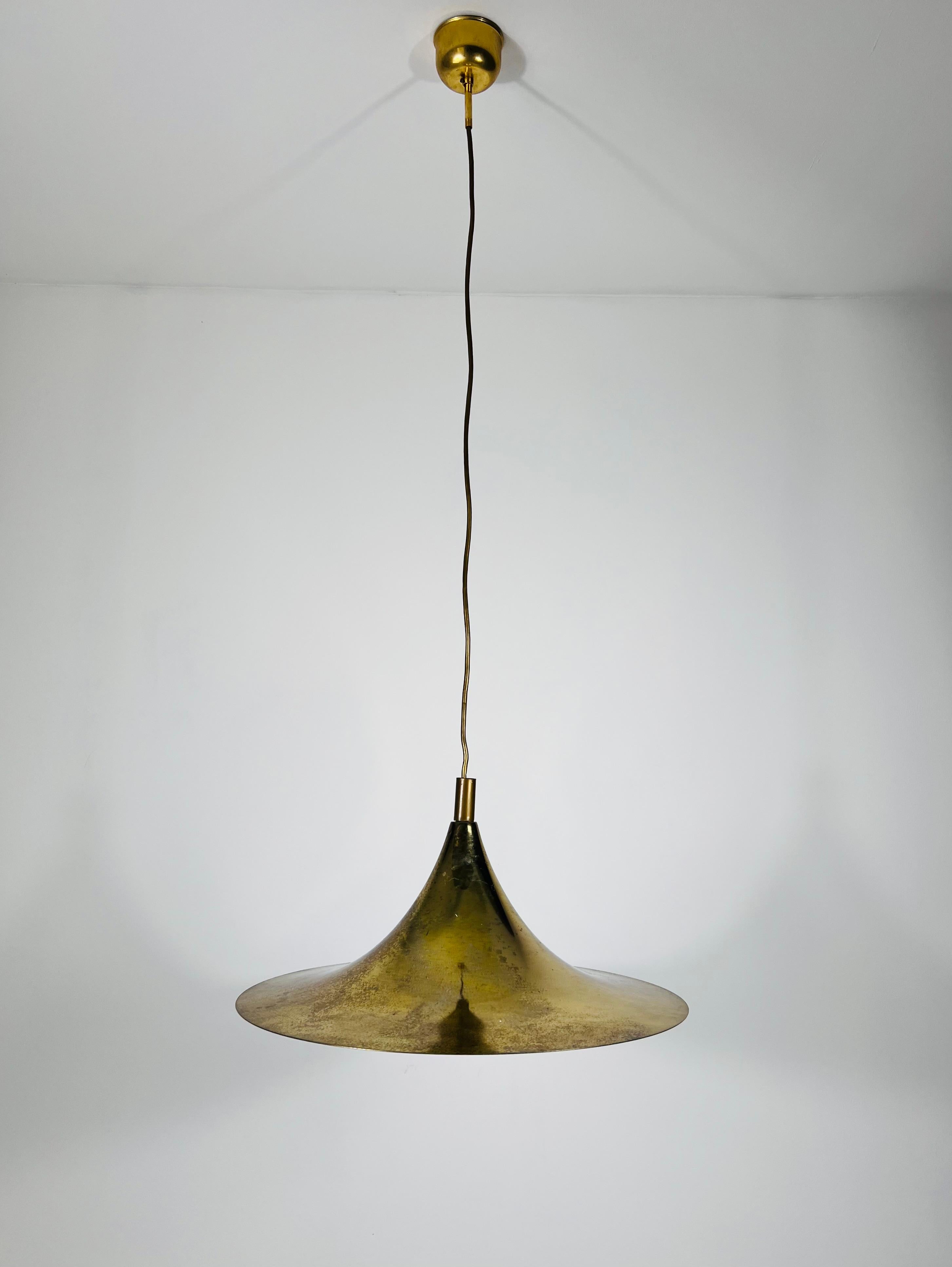 Questa lampada da soffitto di design Fog & Mørup è un pezzo elegante realizzato in alluminio sottile con rivestimento in ottone, a forma di cappello. Caratterizzata da un baldacchino in ottone, questa lampada incarna l'estetica distintiva dell'A