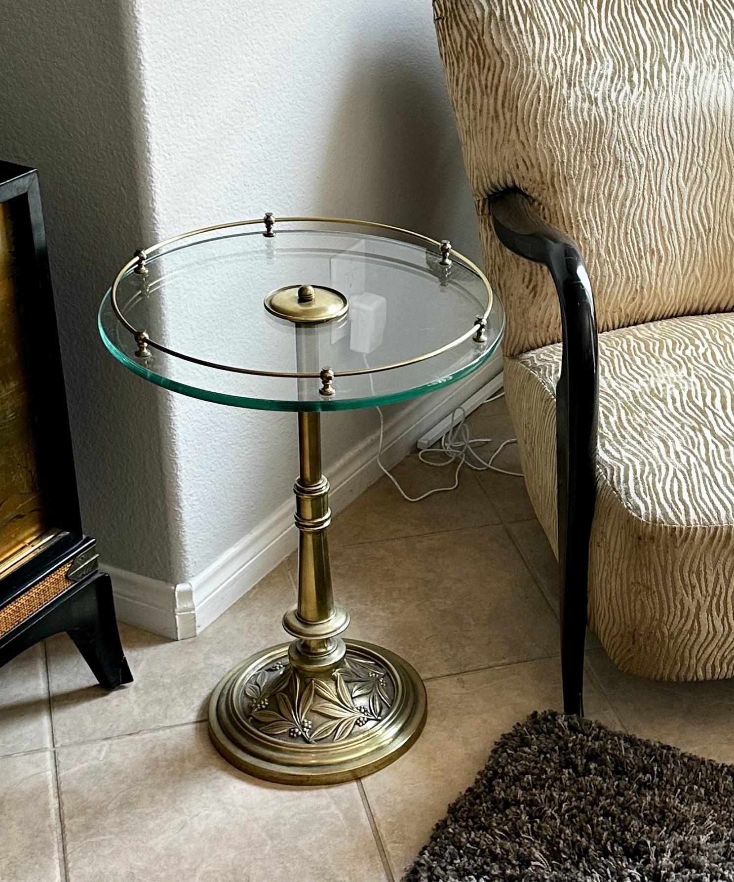1940s brass round side table (or end table) with embossed leaf design detailing on base. Round glass and brass gallery railing is 17