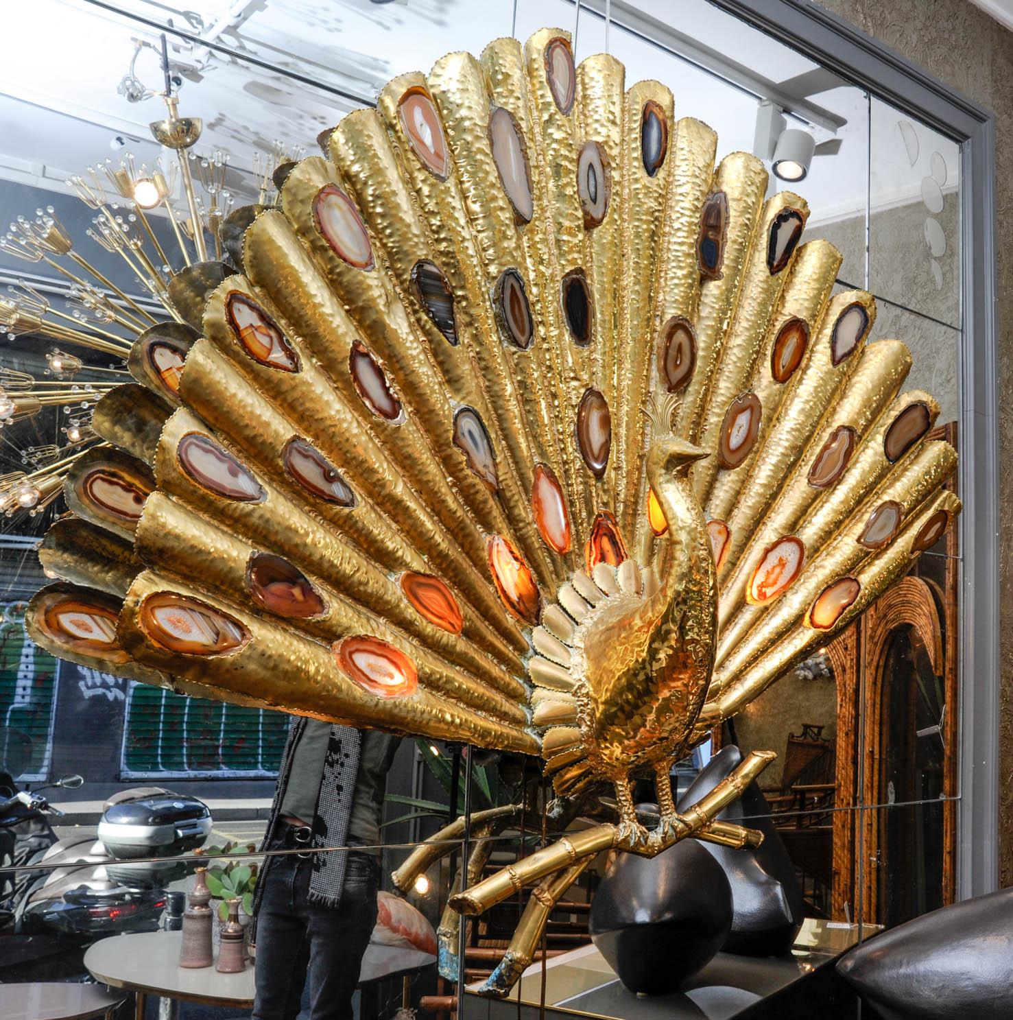 This monumental sconce is a sculptural brass peacock, incrusted with agate stone. Signed by Faure, it is wearing 9 light bulbs