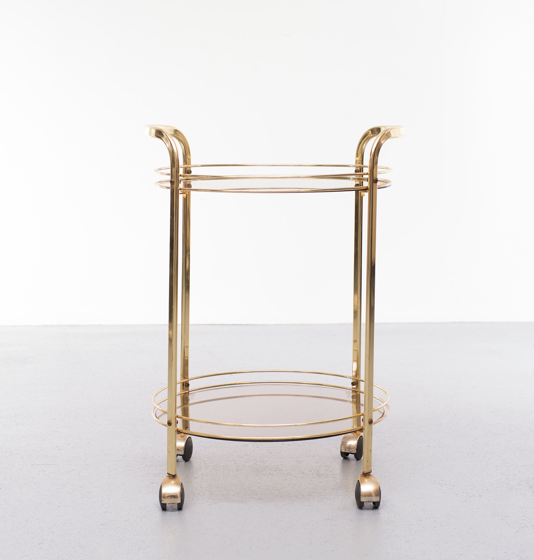 Very nice brass serving trolley. On wheels. Two tier. Smoked glass.
Hollywood Regency in style. Good condition.