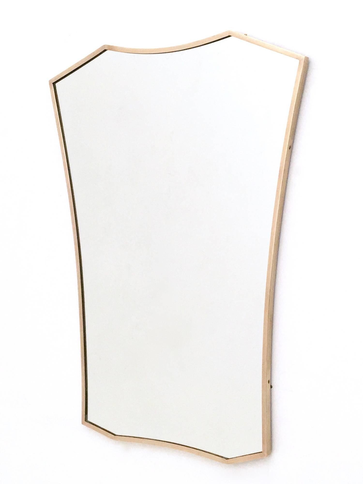 This beautiful shield shaped wall mirror features a brass frame.
It may show slight and imperceptible traces of oxidation, but it is in excellent original condition and it is ready to be hung to a home's wall.

Measures: Width: 60 cm
Height: 84