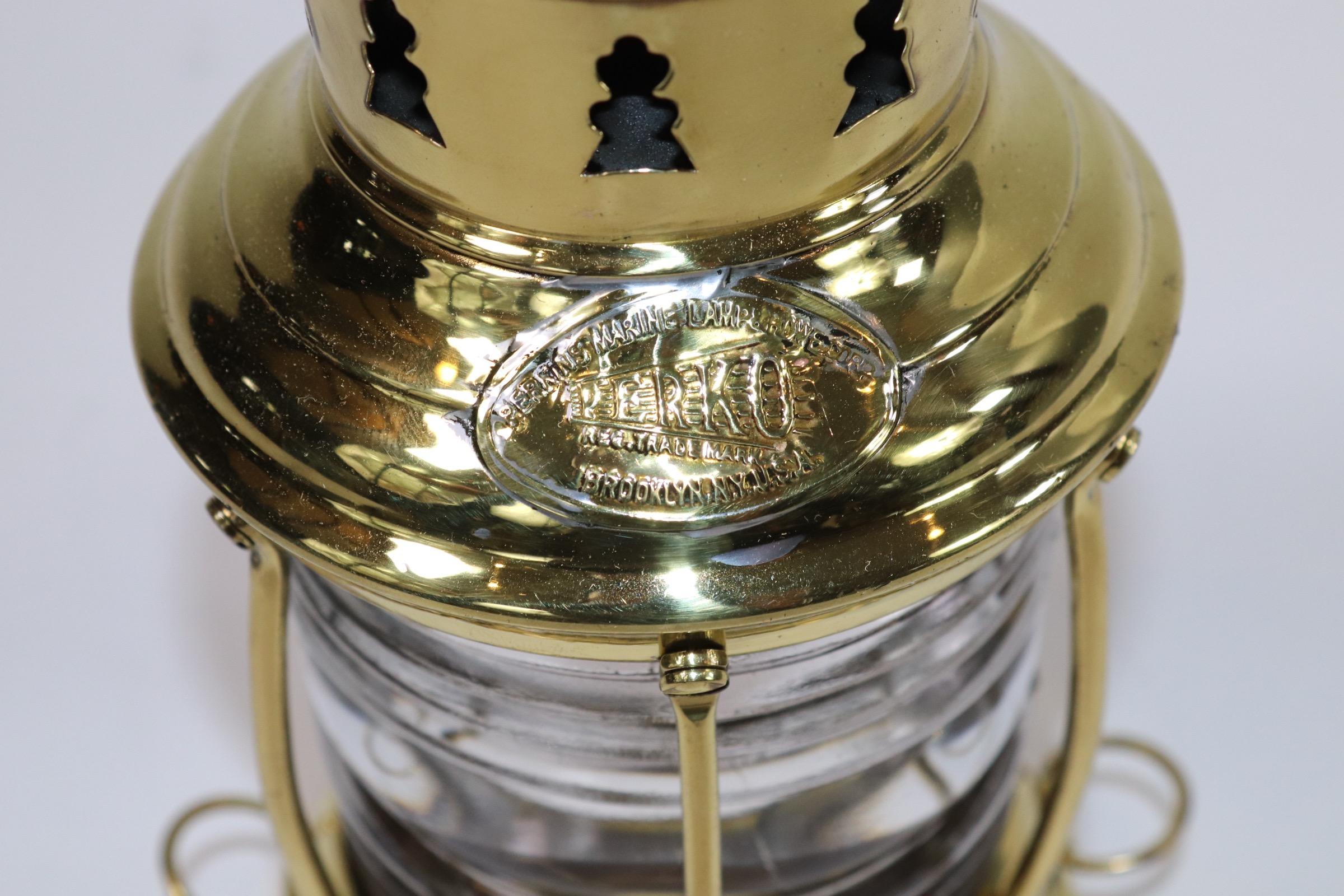 Polished and lacquered brass ships anchor lantern by Perko of Brooklyn. Fresnel glass lens with protective brass bars. With original burner. Weight is 2 pounds.
