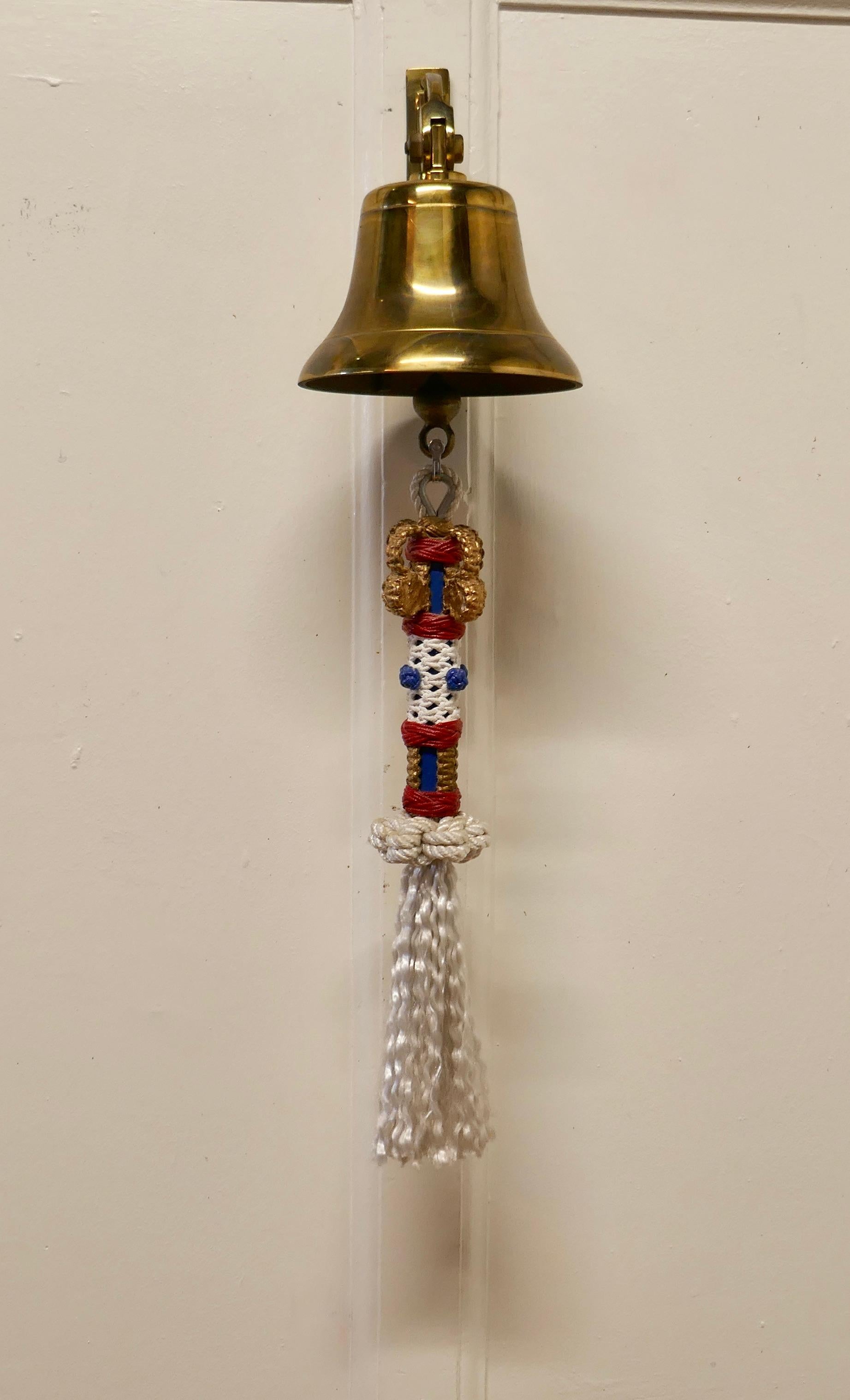 Brass ships bell with royal naval bell rope

Brass Ships Bell on a wall bracket, this good brass bell has a superbly knotted bell rope in Red, White, Blue and Gold for the Crown at the top
The bell is complete with clapper, it is in very good