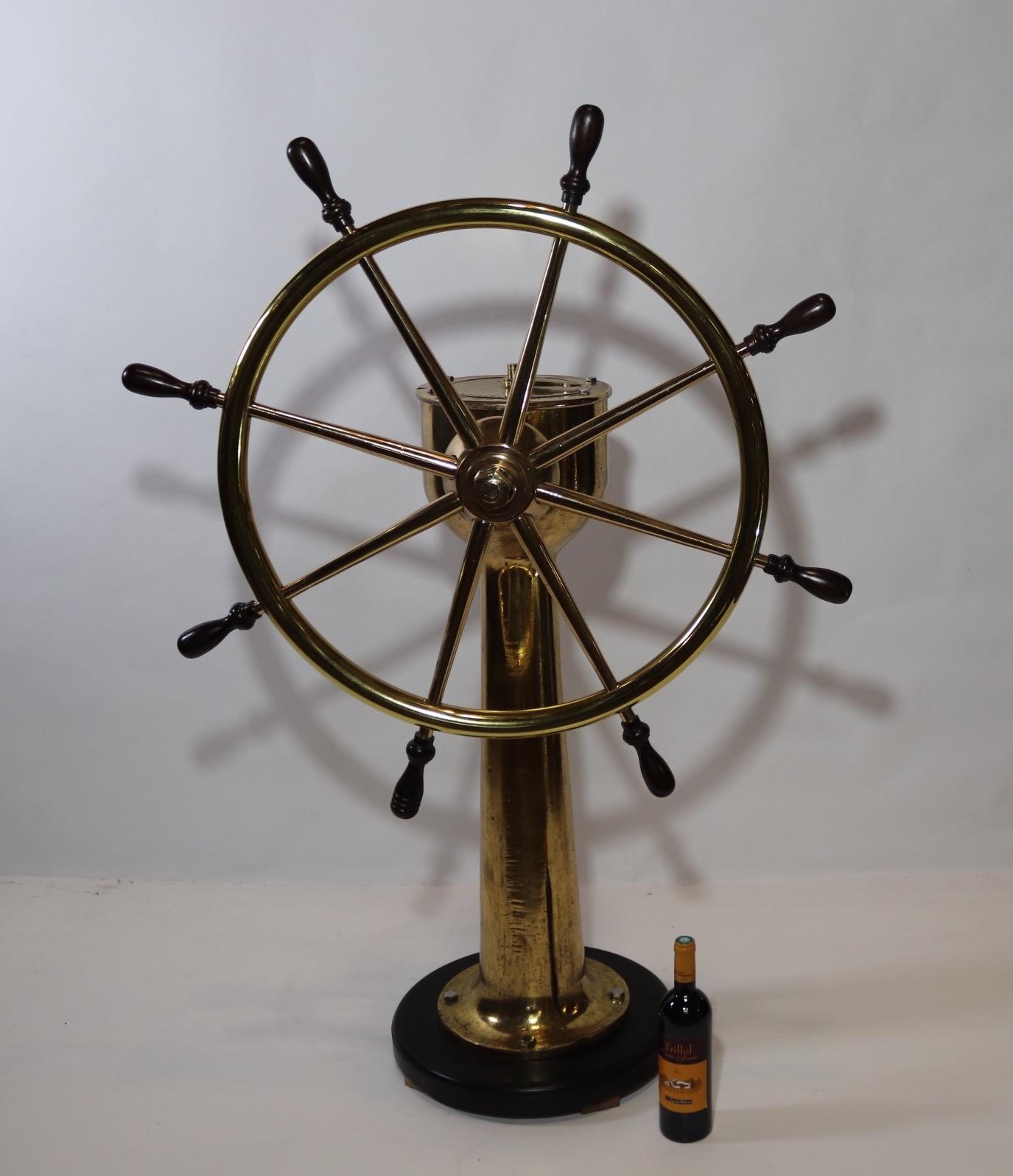 Exceptional ships wheel of solid brass that has been meticulously polished and lacquered to create quite a display. Wheel is fitted with eight turned wood handles. The substantial brass pedestal is mounted to a thick wood base with routed edge and