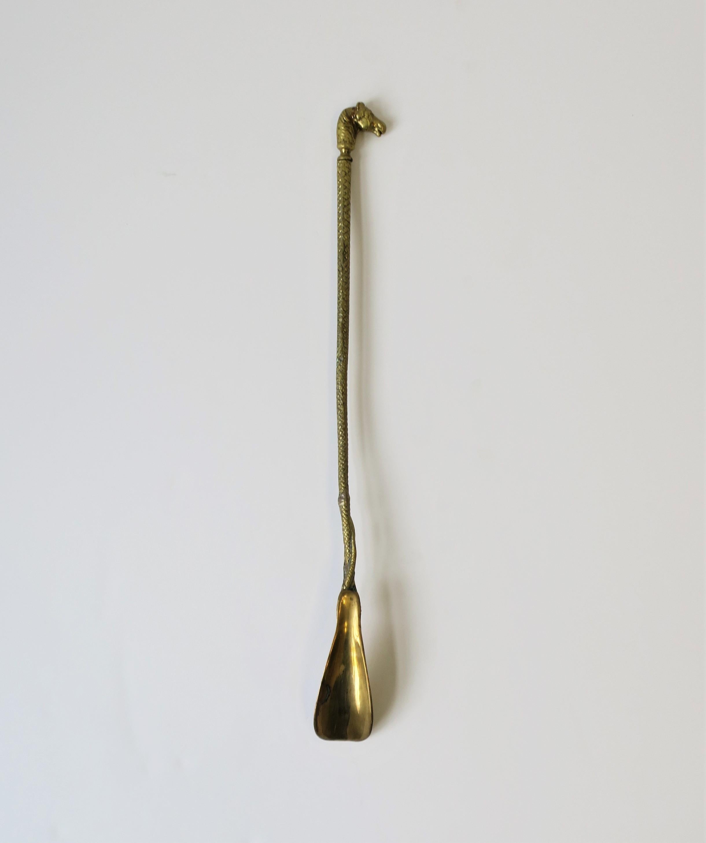 A solid brass vintage shoe horn with horse head and serpent snake design, in the style of Gucci or Hermes, circa 20th century. Equine horse head at top, serpent snake design textured handle with snake head at base near 'horn'. Dimensions: 18