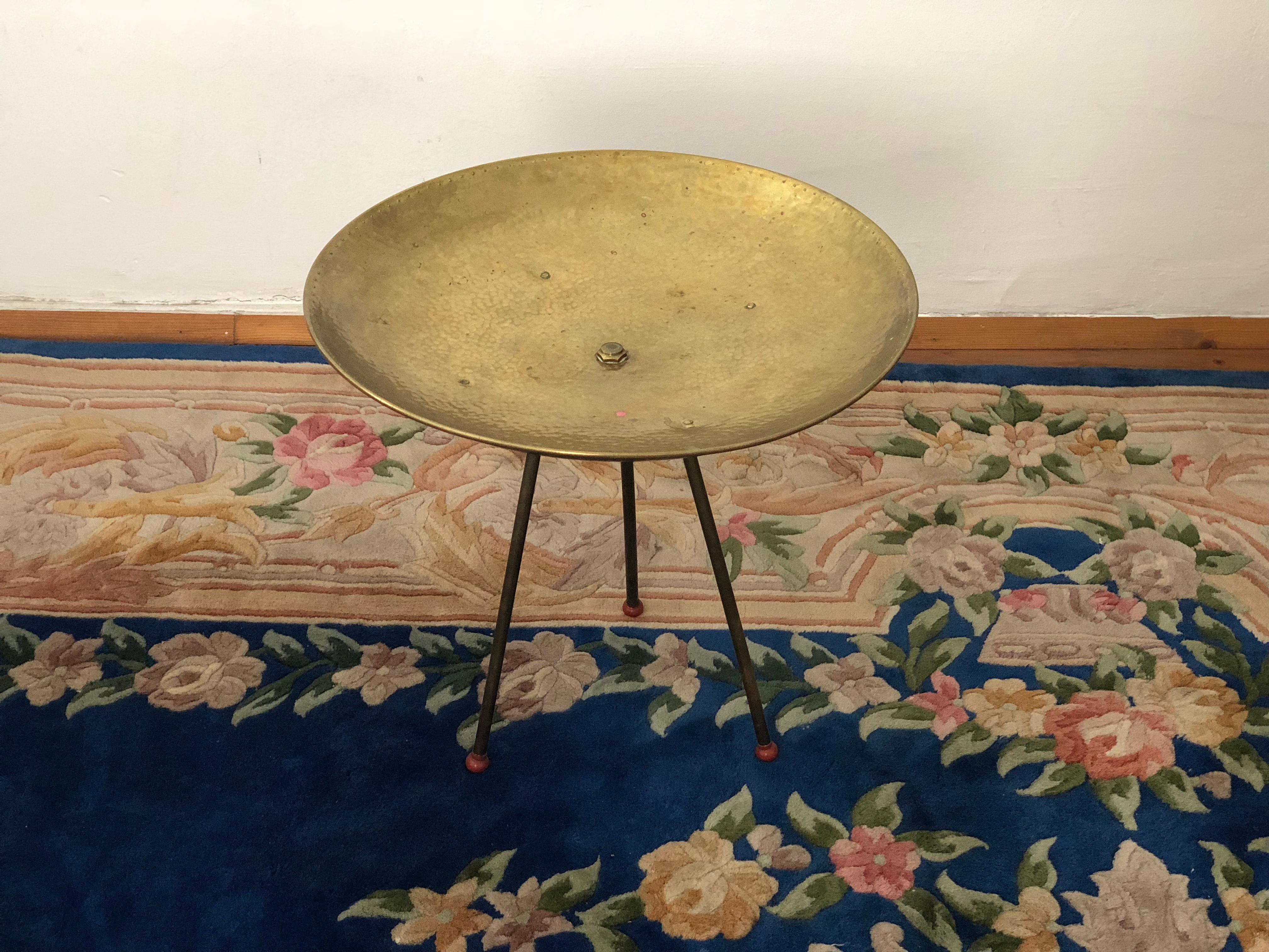 We would love to discover who actually designed this beautiful brass side table in bowl shape. It is so adoring and functional! Regardless of attribution this table is wonderful.
It is made out of hammered brass and stands on three legs with red