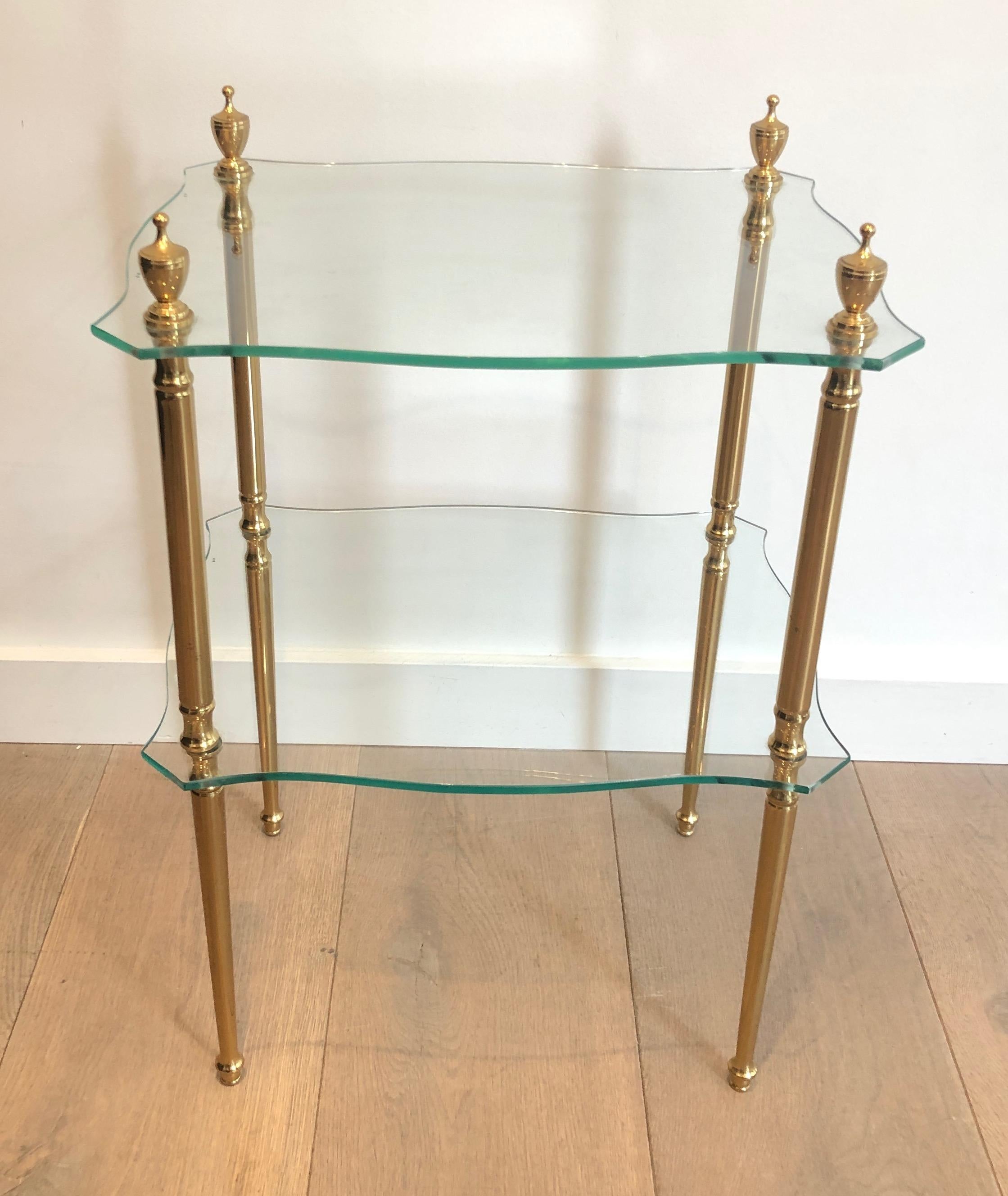 This neoclassical style side tableis made of brass with fluted legs and 2 glass shelves. This is a work by famous French designer Maison Jansen. Circa 1940.