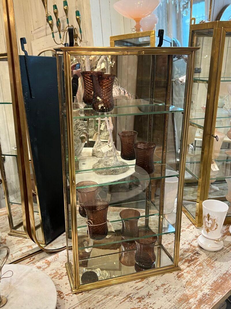 Elegant display cabinet from circa 1930s France, in stringent Art Deco style with its simple and tight profile.

The wall hanging display case is manufactured by SIEGEL PARIS (see image of stamp), is in quality brass, has 3 beautiful glass shelves