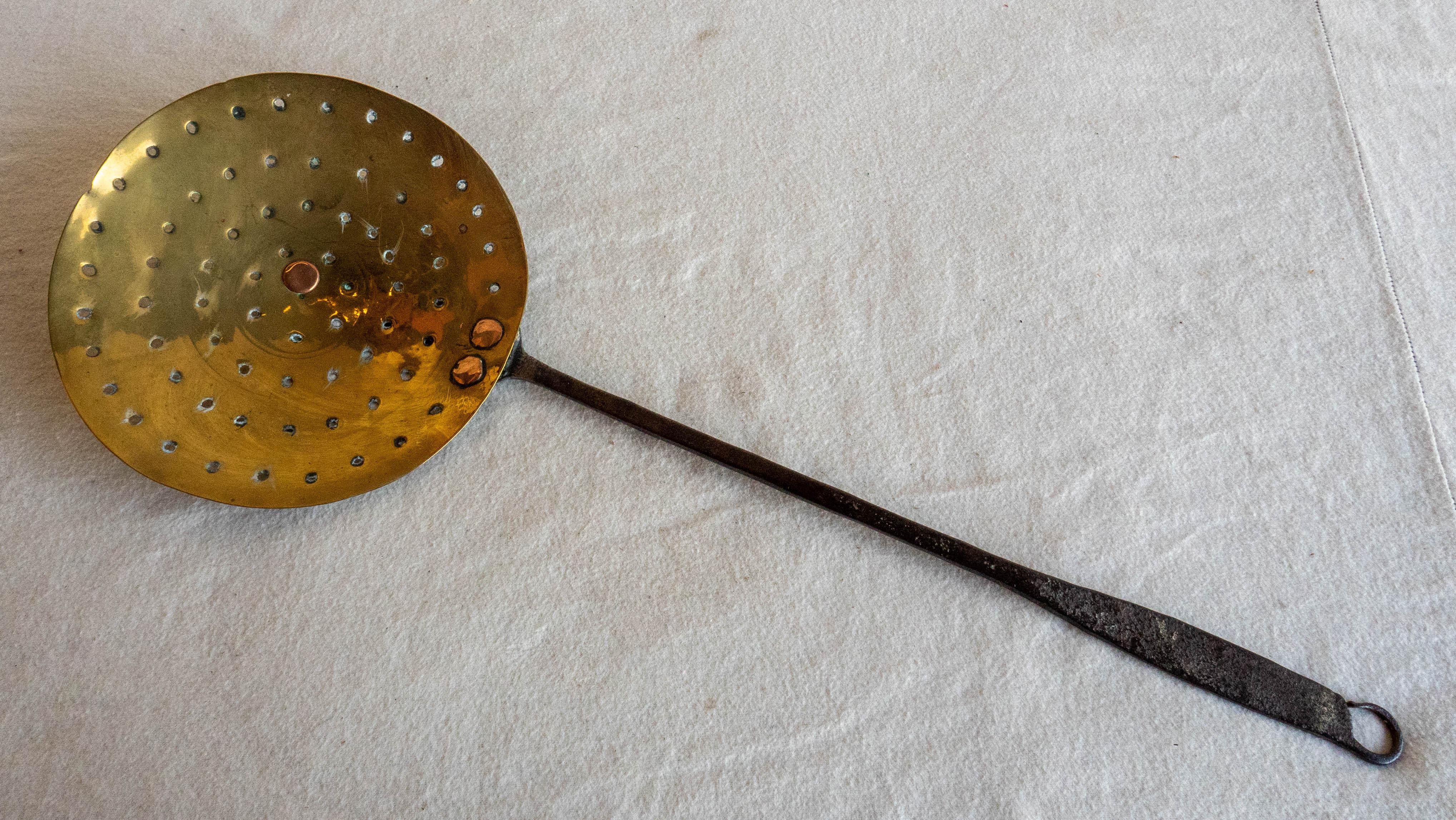 Early 19th century English brass sieve with concentric piercings in bowl and steel handle, circa 1820.