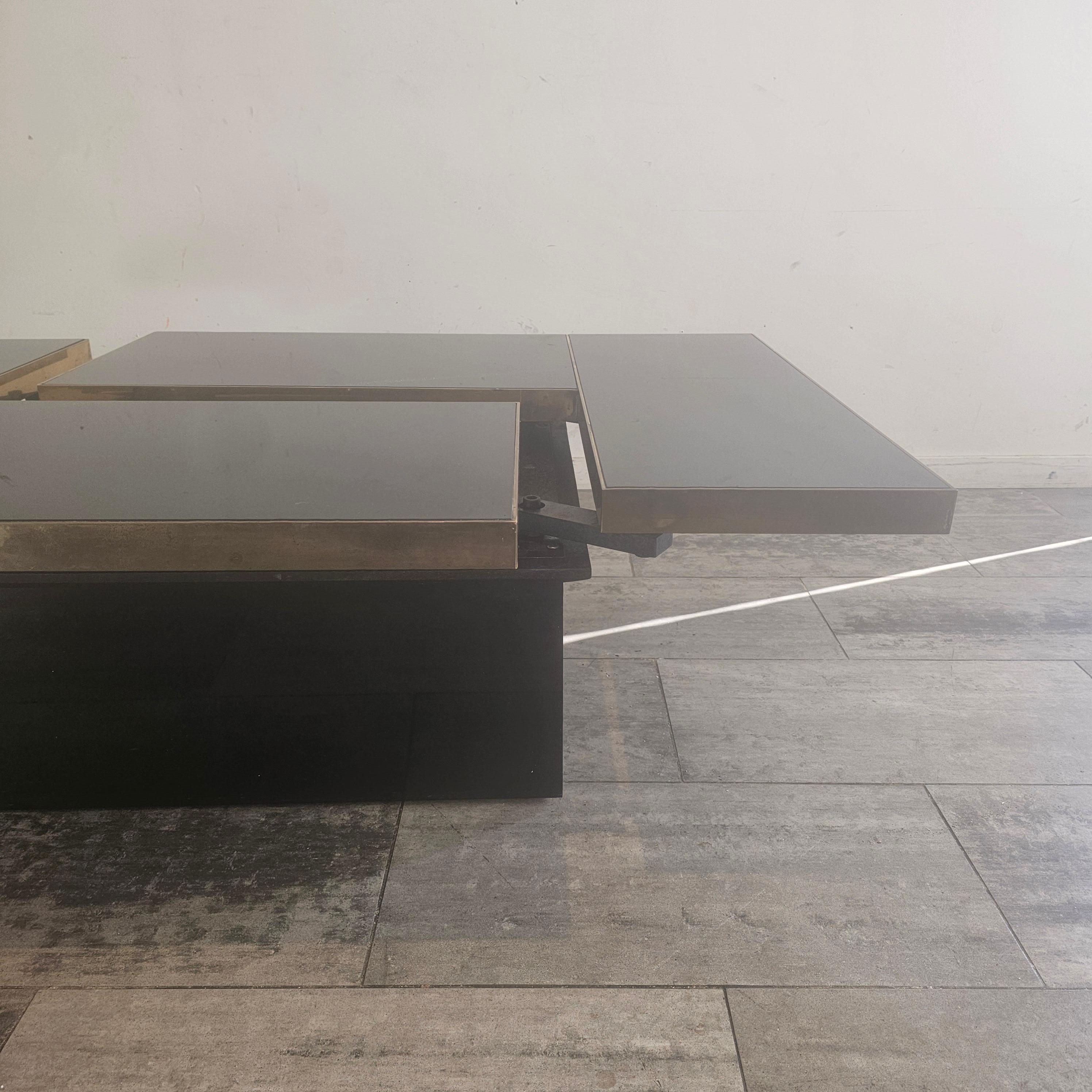 Mesa muy singular con tablero deslizante, debajo un compartimento completo de bar con espejos.
La parte superior es de cristal negro espejado y la alimentación tiene 4 cristales negros espejados. La mesa de centro está atribuida a la 