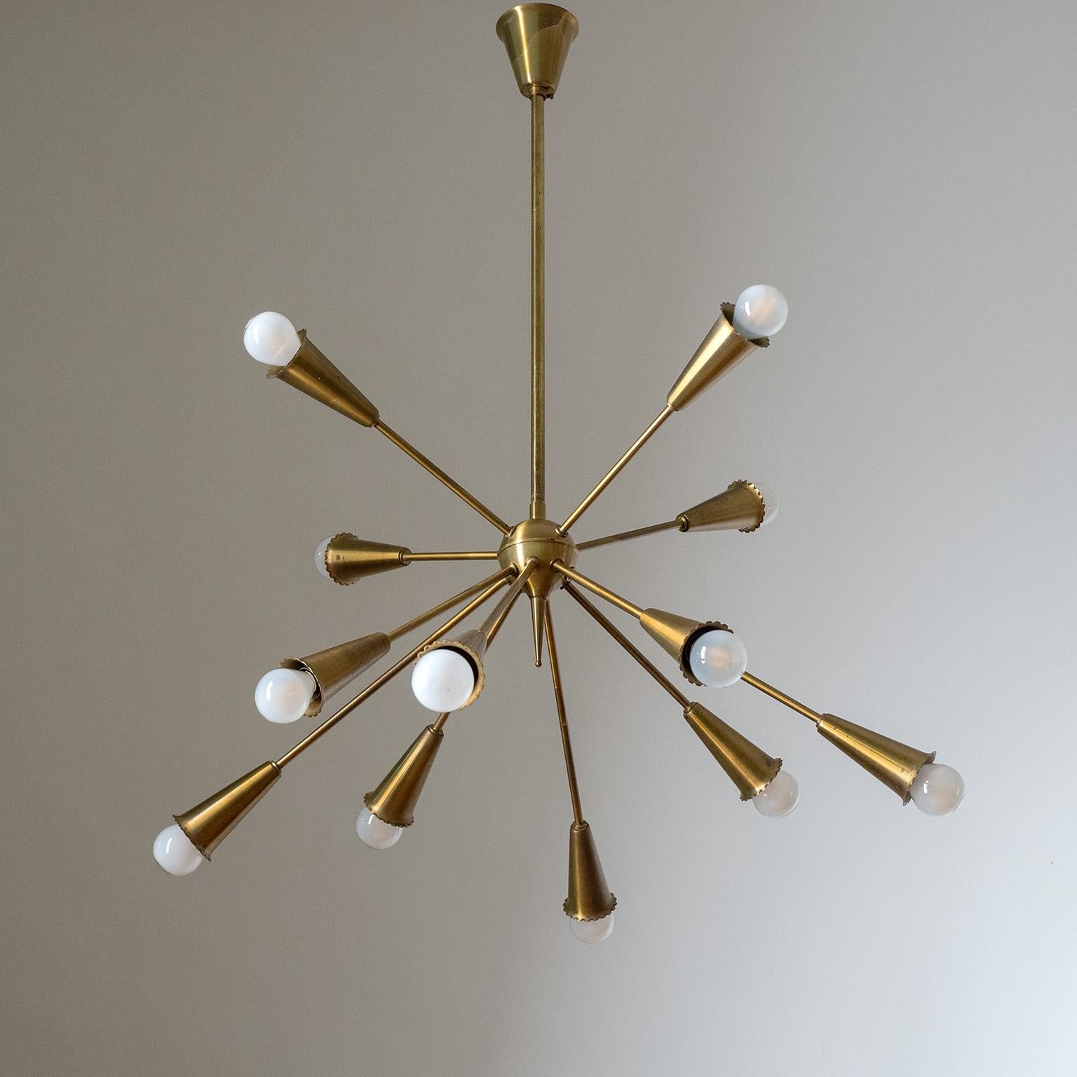 All brass sputnik chandelier from the 1950-1960s. Twelve arms in two different lengths emanate from a brass centerpiece and end in a brass socket cover with a rare ‚frilled‘ rim. Each arm has an original brass E14 socket with new