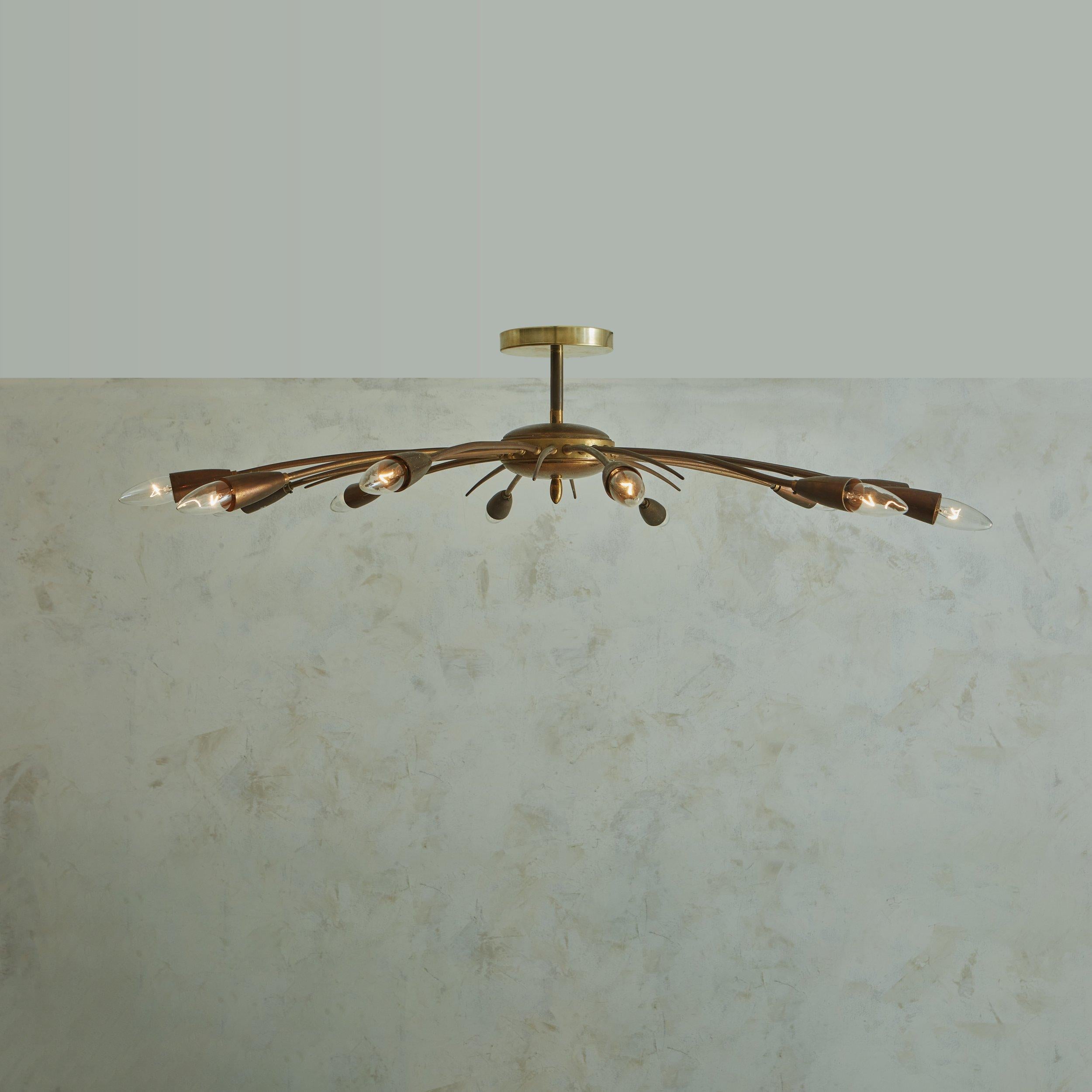 A 1960s Italian chandelier in the style of Stilnovo. This fixture was constructed with patinated brass and features 12 tubular arms, which sprout outwards from a central sphere with a bottom finial. 12 additional shorter decorative tines sprout in