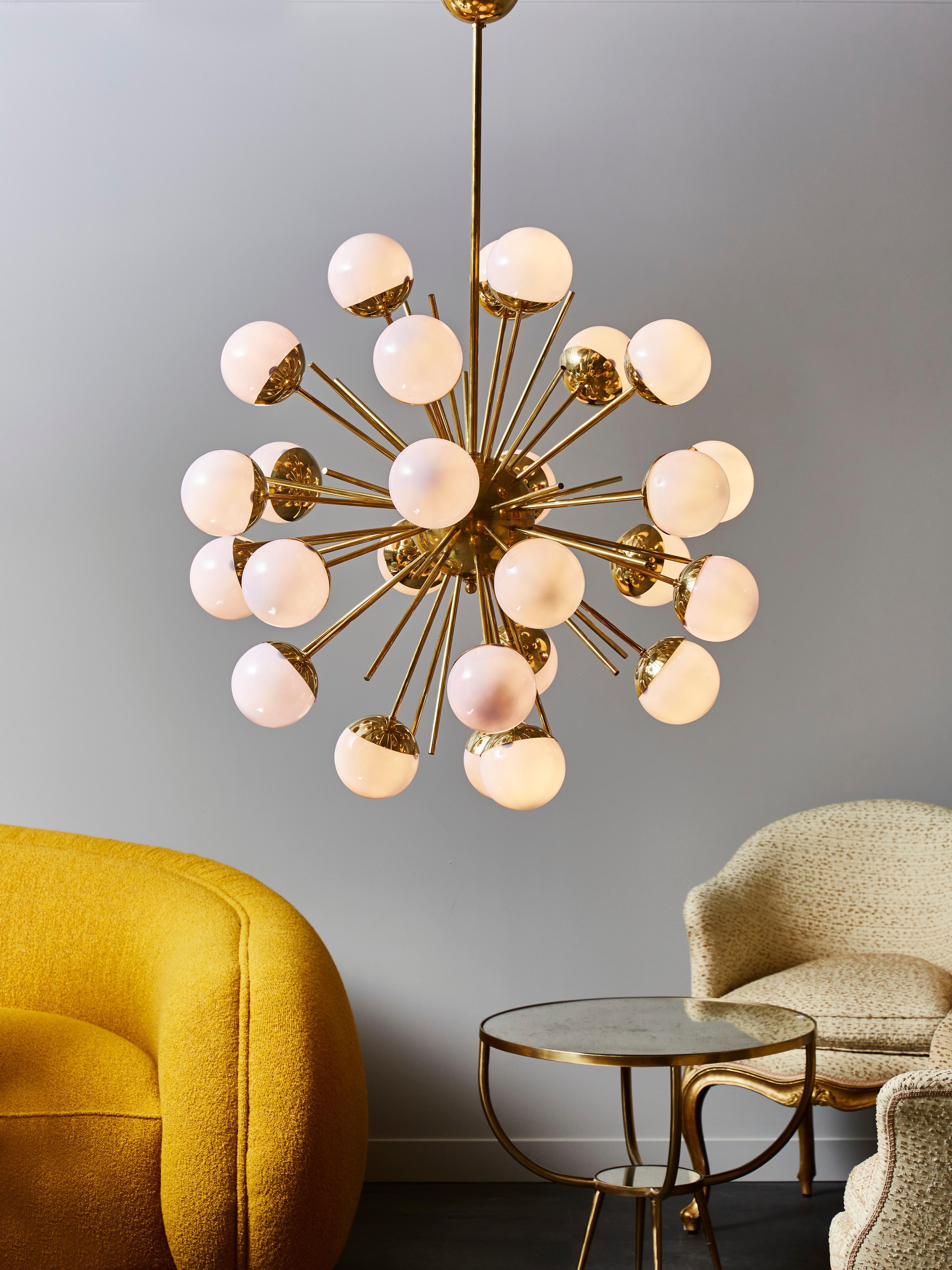 Sputnik style chandelier made of a brass structure and twenty six arms of light.

Each of them is ornated with a light purple tinted glass globe hiding the light bulb.

When lighted on, the globes keep a very light shade of purple.