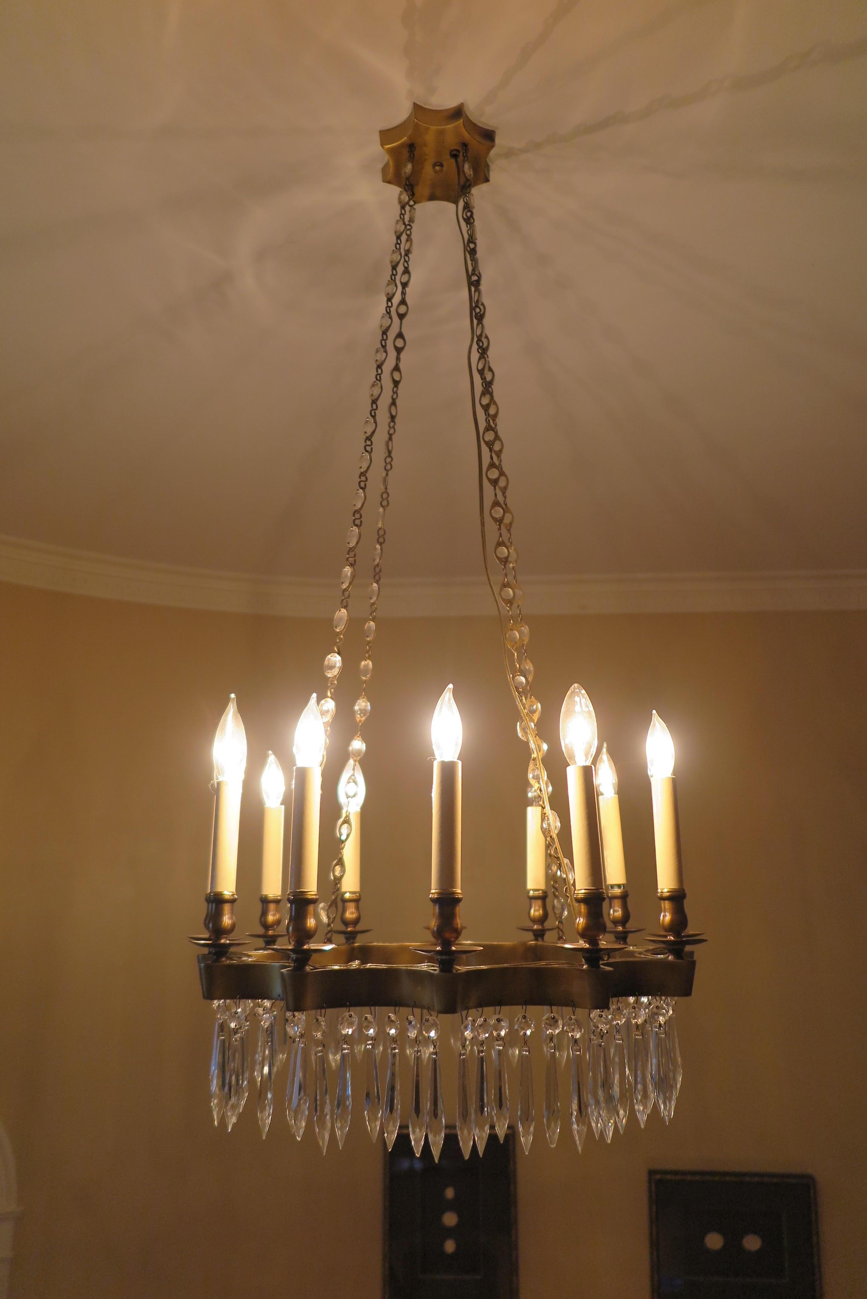 Brass bronze star burst and crystal chandelier. Early midcentury 1940-1950 possibly earlier. Brass bronze star shape frame and canopy with hanging crystals having 12 lights. 
Illuminates beautifully. Very good condition.