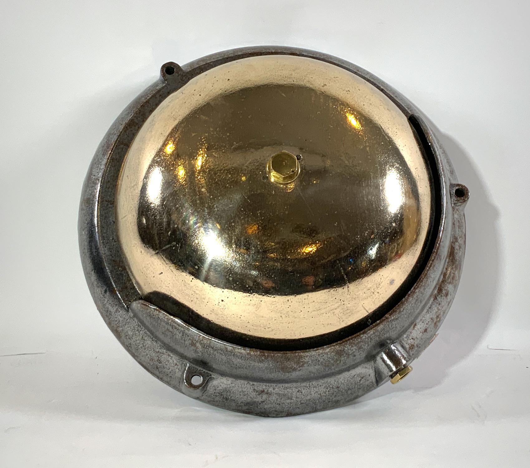 Grande cloche de salle des machines d'un navire. La cloche en laiton poli est montée sur un boîtier en acier lourd. Une grosse pièce d'équipement industriel maritime. Très décoratif. Vers 1950.