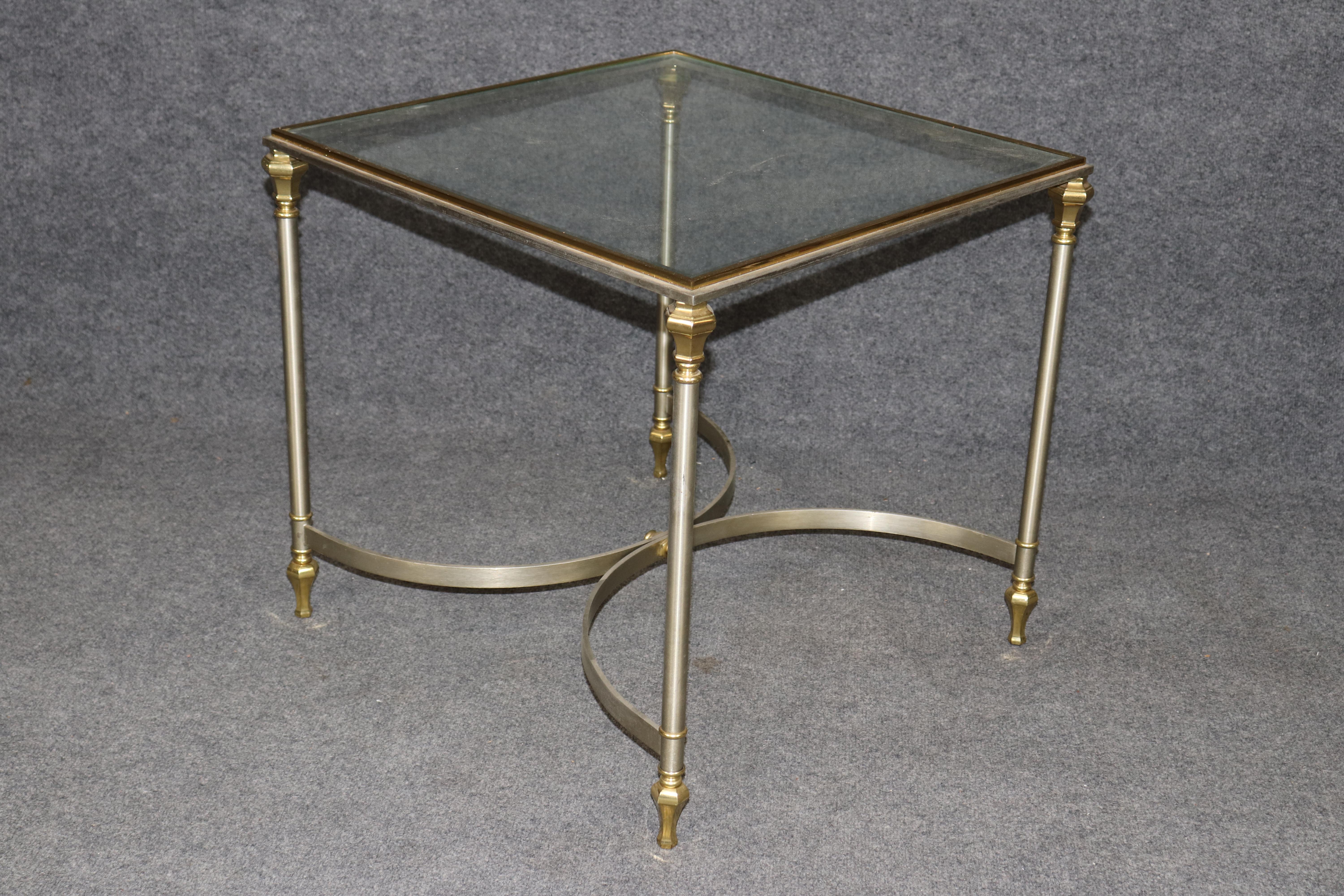 Il s'agit d'une magnifique table d'appoint en acier massif, laiton et verre, extrêmement bien fabriquée. La table est en très bon état et est à la manière de la Maison Jansen. La table peut présenter quelques légères éraflures sur le plateau en