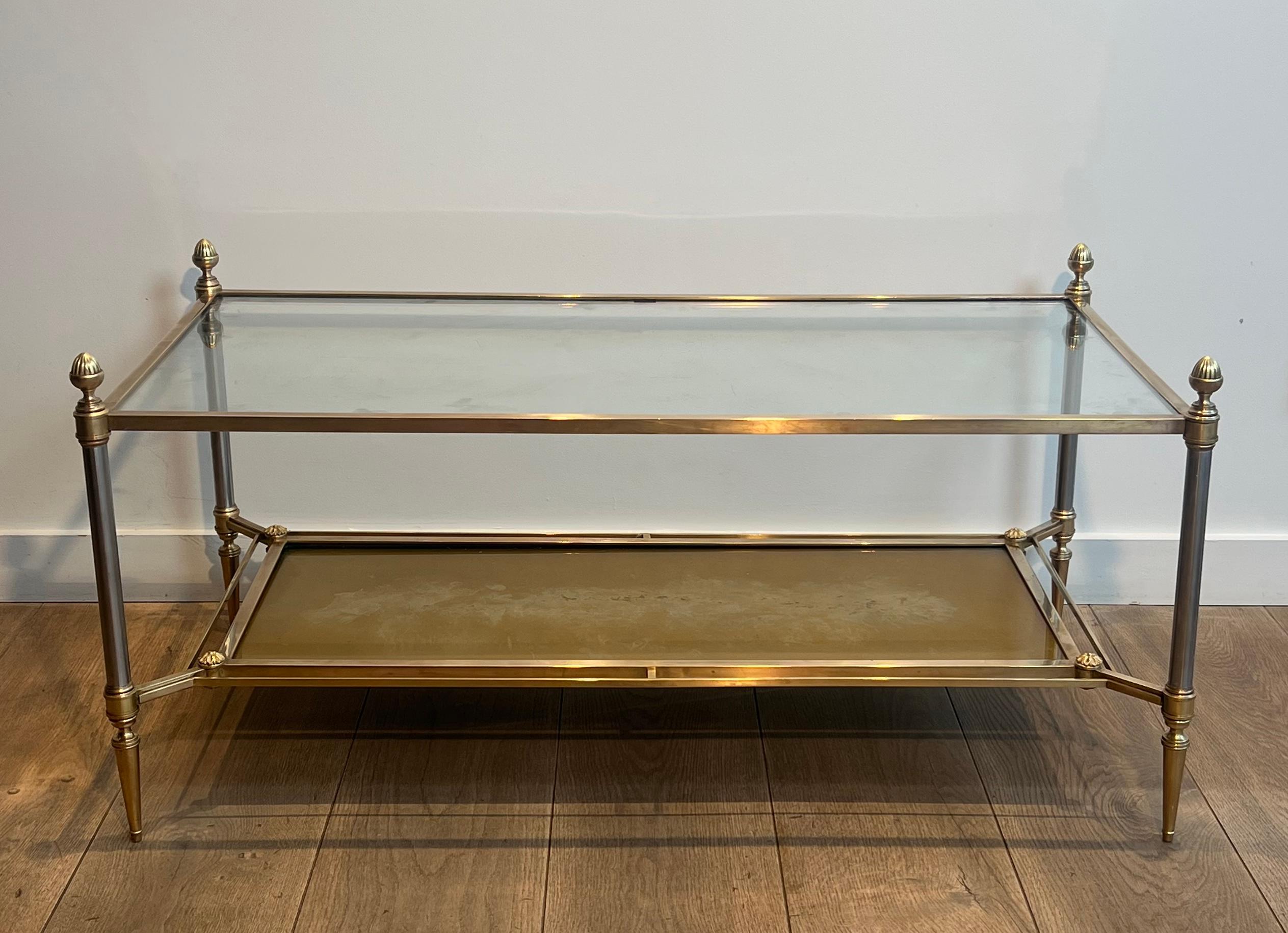 This beautiful and elegant neoclassical style coffee table is made of brass, brushed steel and bronze with clear glass on top and gilt eglomised mirror bottom shelf. French work by Maison Jansen. Circa 1940