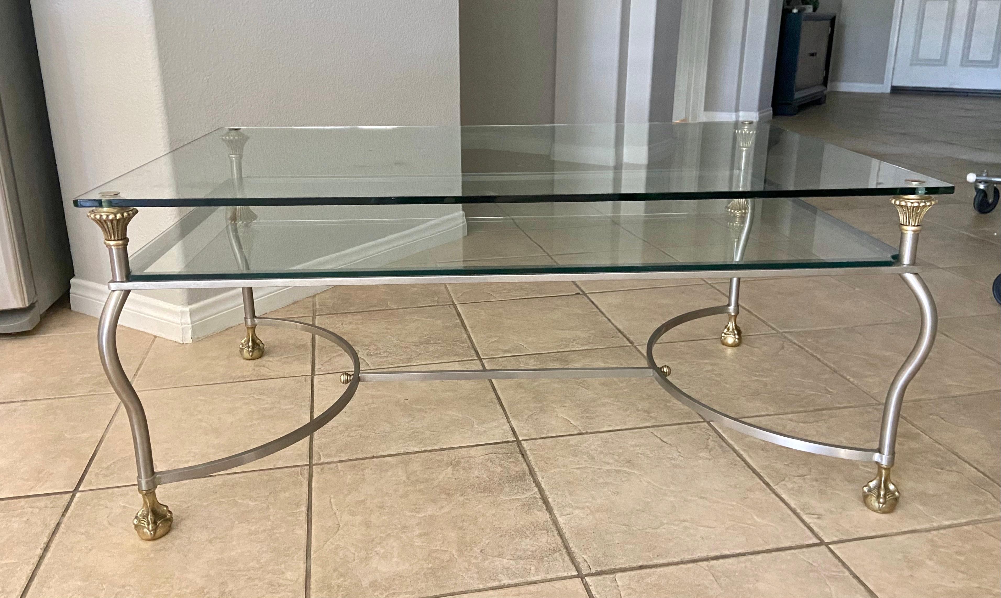 Italian made steel and brass two tier glass inset cocktail table with claw feet detailing. The well constructed table shape is rectangle with nicely detailed brass fittings. Stamped on foot 