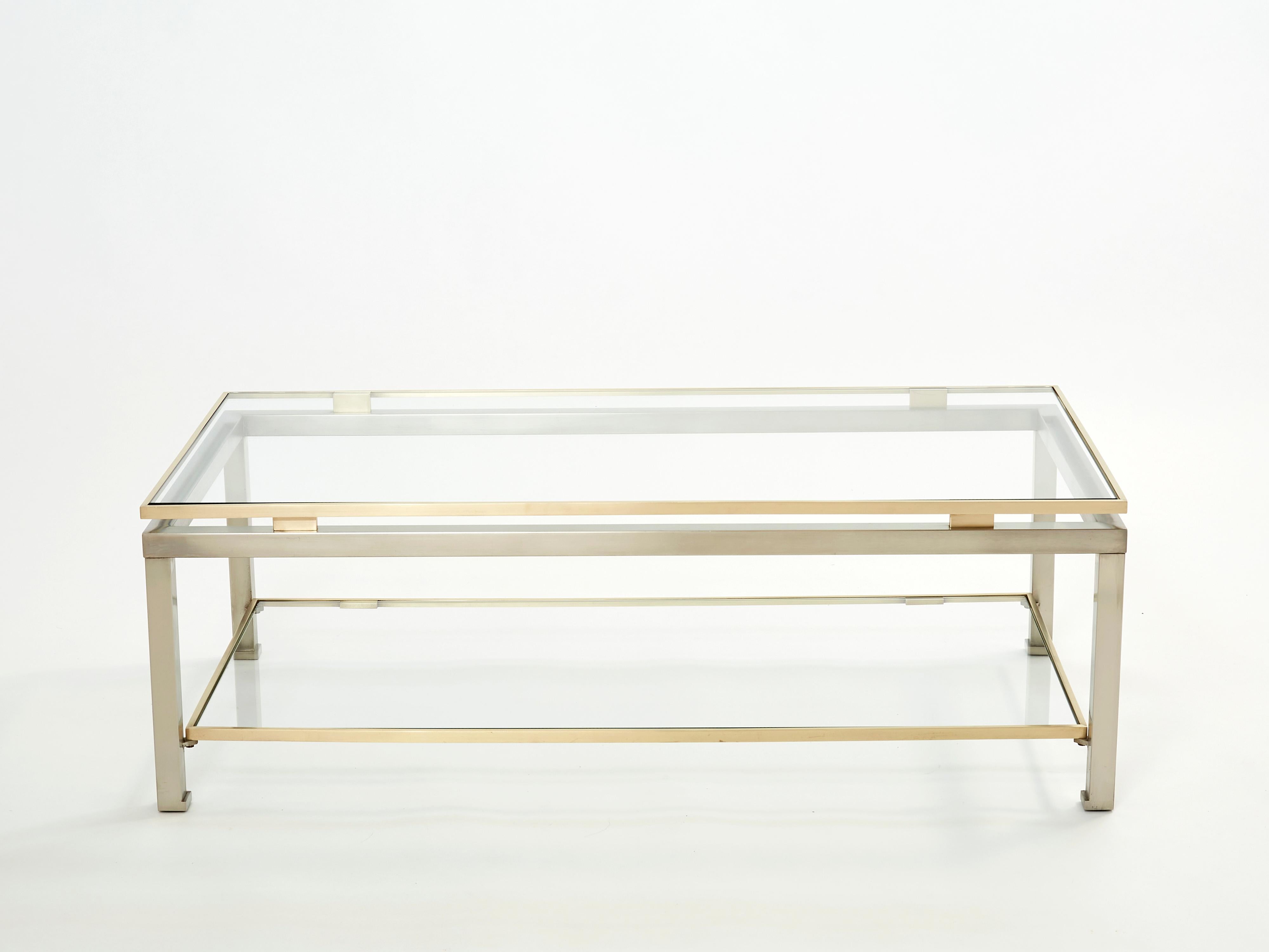 Simple lines point to this two-tier coffee table's French mid-century roots. Designed by Guy Lefevre for Maison Jansen, it features smooth steel legs with a brass top and accents, and transparent glass tops. Its symmetry, elevated glass, and strong