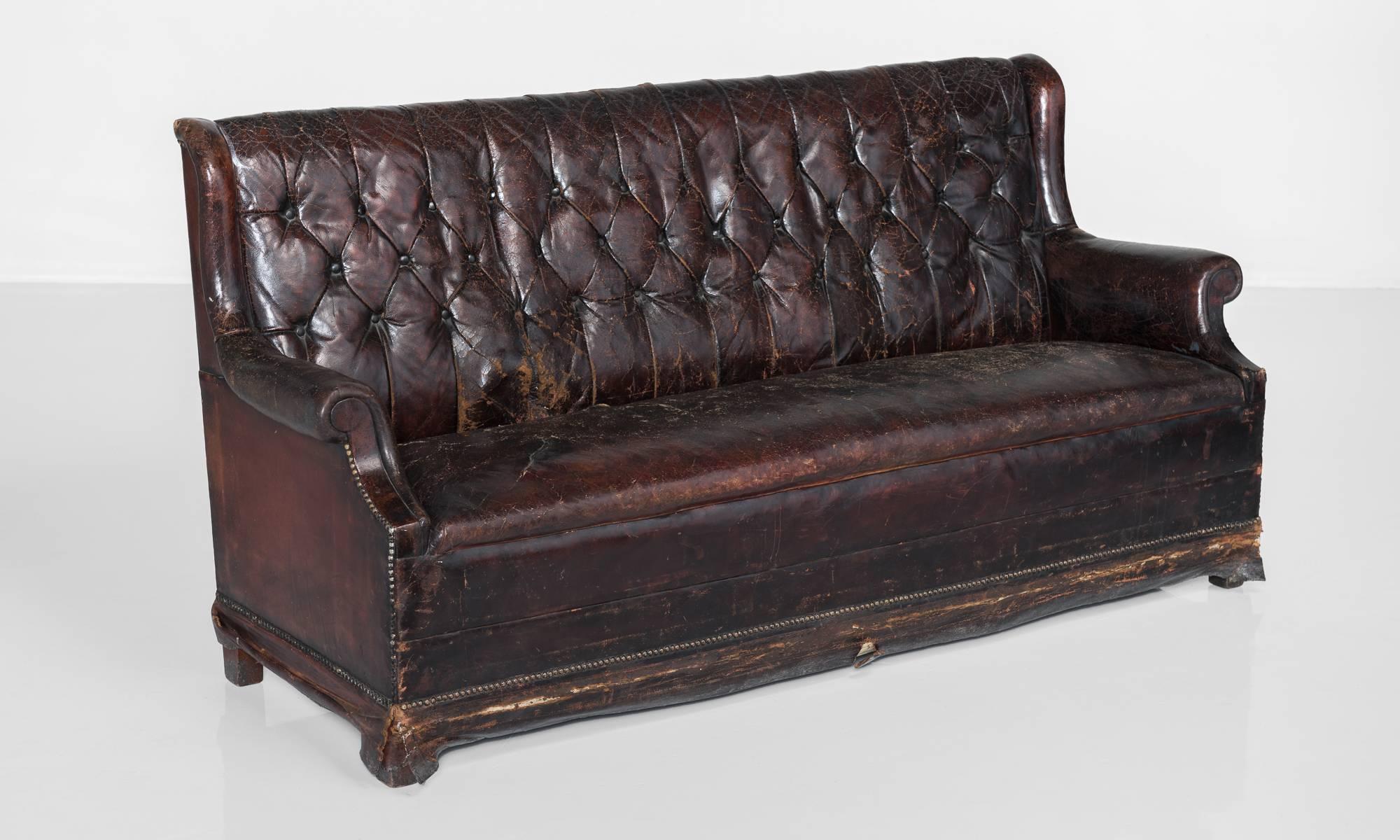 Brass studded leather club sofa, England, circa 1860.

Dark leather upholstery with roll over arms on block feet.

Measures: 75.25
