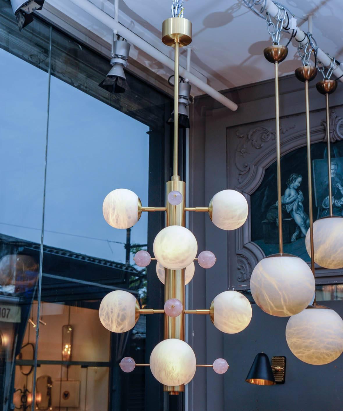 Delicate suspension made of satin brass vertical structure holding enlighten alabaster globes and small quartz rose spheres.