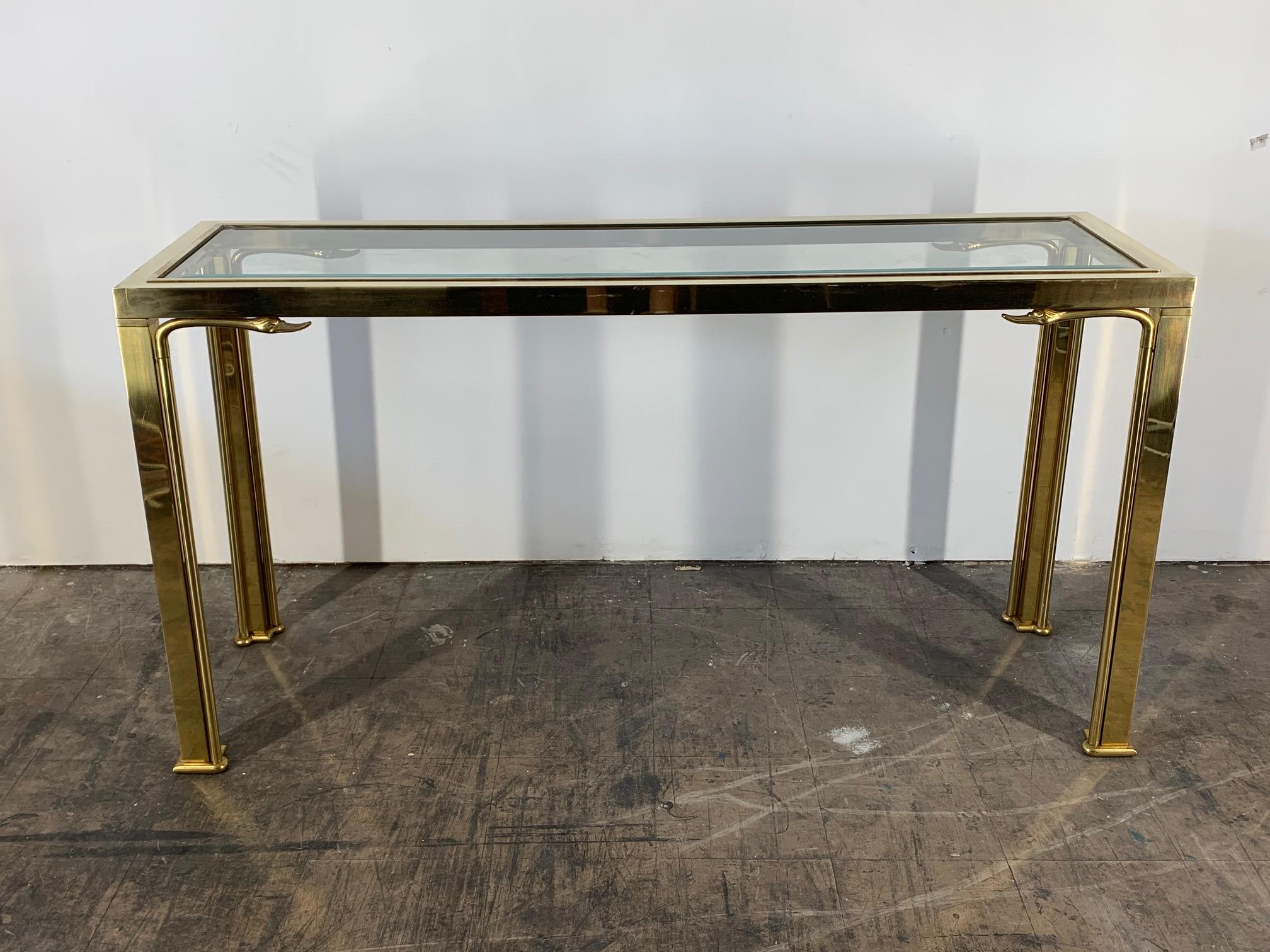 Brass console table by Mastercraft features swan head motif and bevelled glass top. Good vintage condition with wear consistent with age.