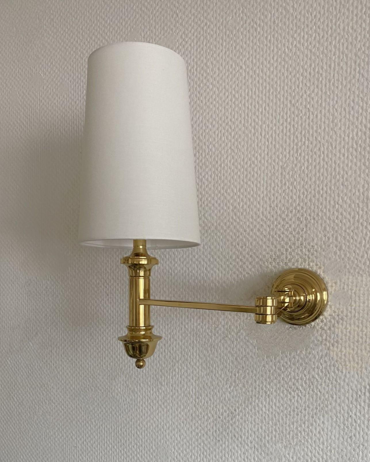 Lámpara de pared de brazo oscilante macizo de alta calidad, estilo Maison Jansen, Francia, años 60. Artesanía precisa de latón pulido forjado a mano con pantalla de lino blanquecino. Este aplique de pared es una rareza del diseño de los años 60 que